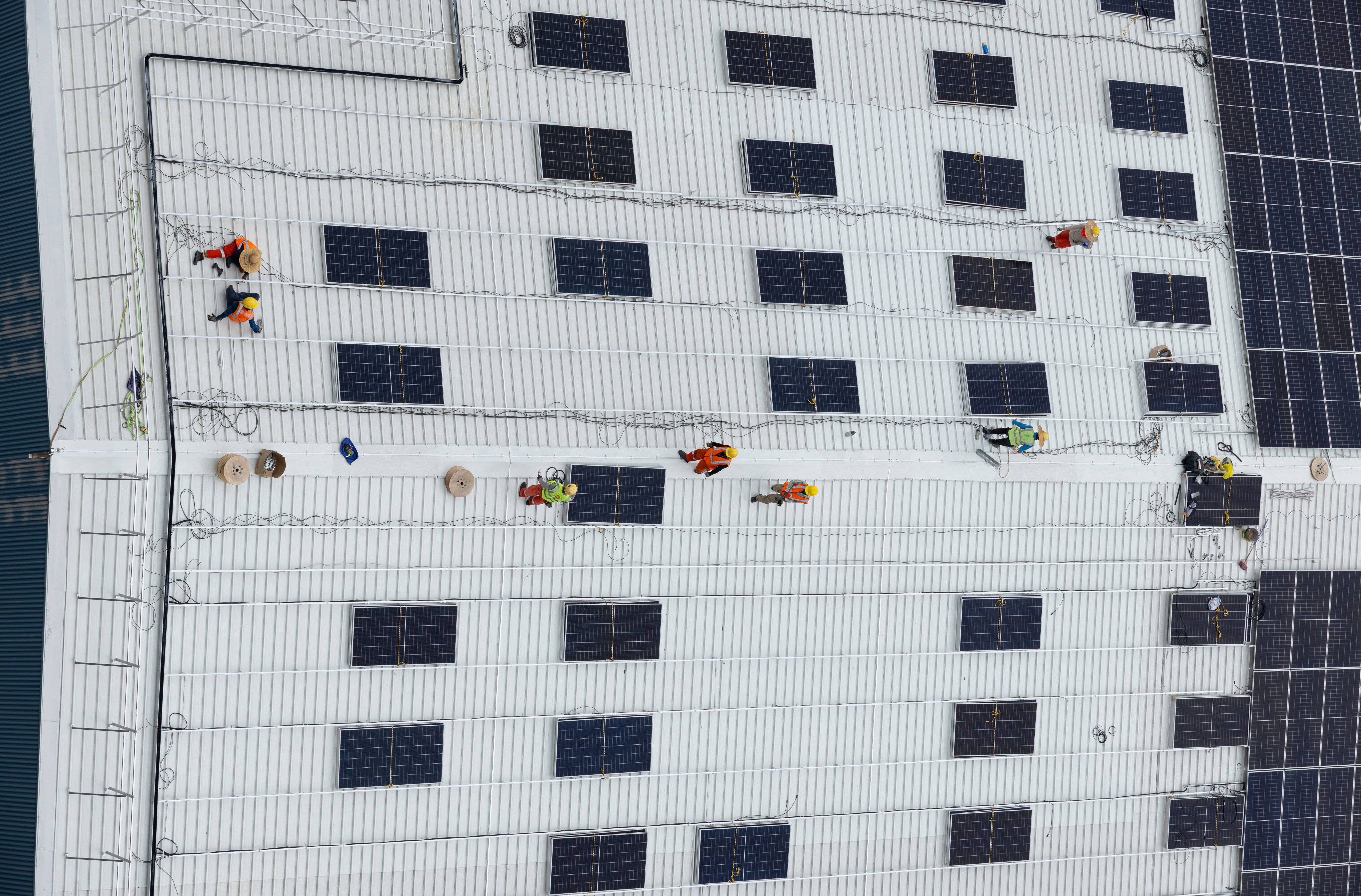 Workers install solar panels on the roof of a warehouse near Jurong Island in Singapore last year. Photo: AFP