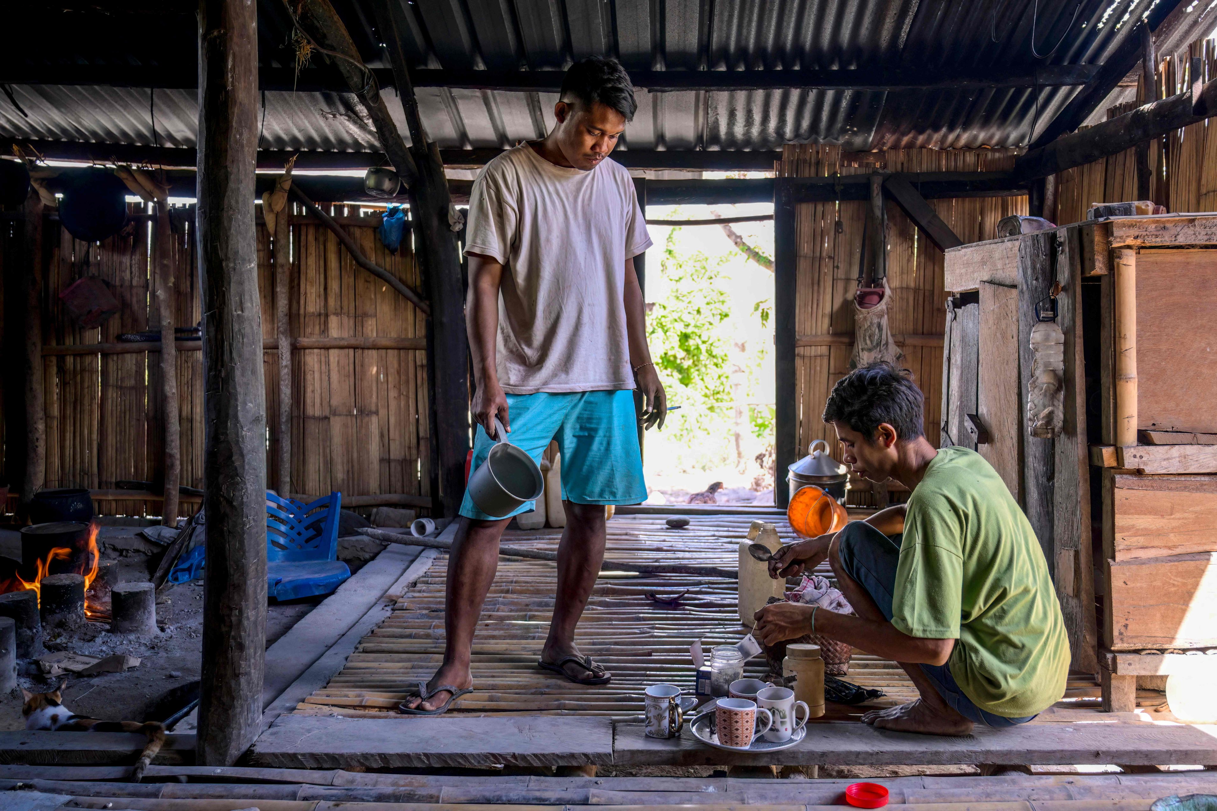 Umbu Ana Rara (left) watches as his “ata”, Kanisius Kanyali Hambarita, prepares drinks at Tanggedu village in East Sumba on June 23. Photo: AFP