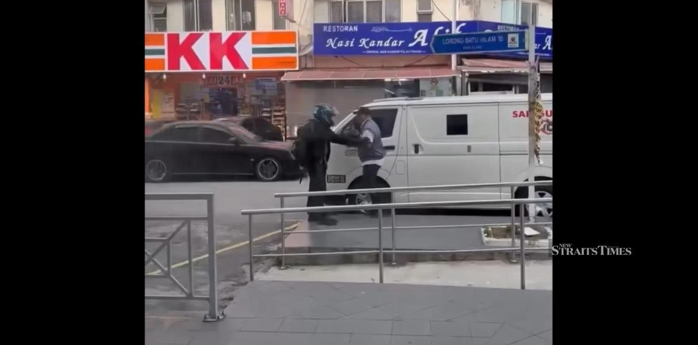 A screengrab shows a robber holding up a security guard outside a bank in Klang on Monday. Photo: Instagram/suaramalaysiabaru