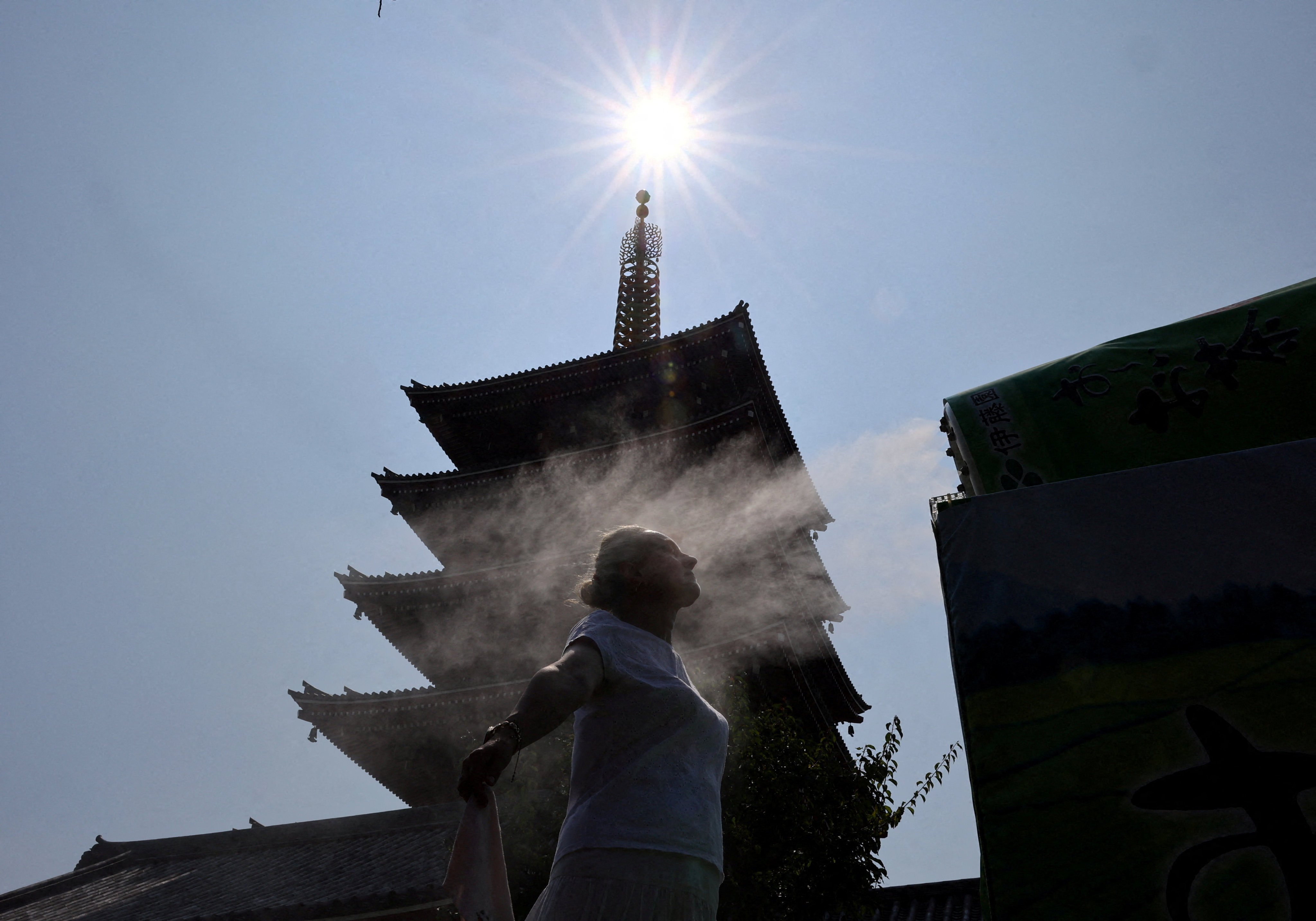 A visitor stands next to a cooling mist at Sensoji temple in Tokyo on Wednesday. Photo: Reuters