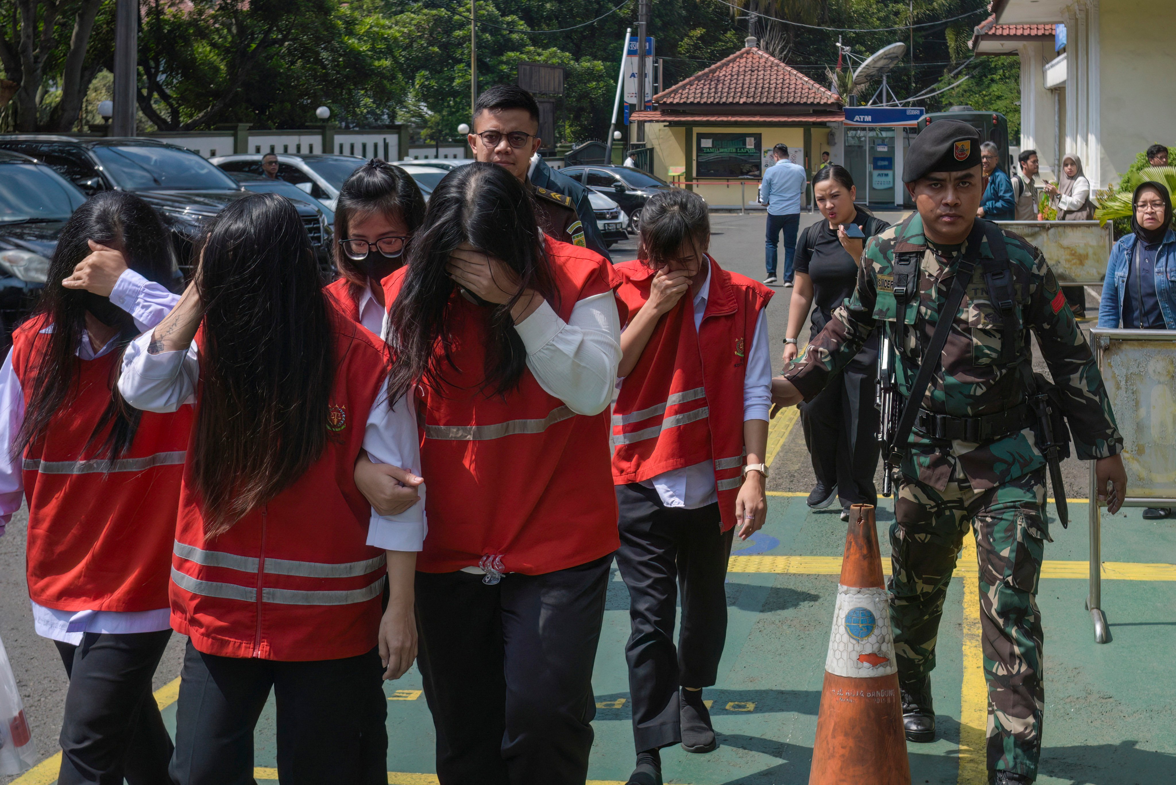 An Indonesian military officer escorts defendants to a trial in a baby trafficking case at the Bandung District Court in Bandung, West Java, on July 21, 2026. A woman who led a baby trafficking ring in Indonesia was sentenced July 21 to seven years in prison, a judge said. (Photo by TIMUR MATAHARI / AFP)