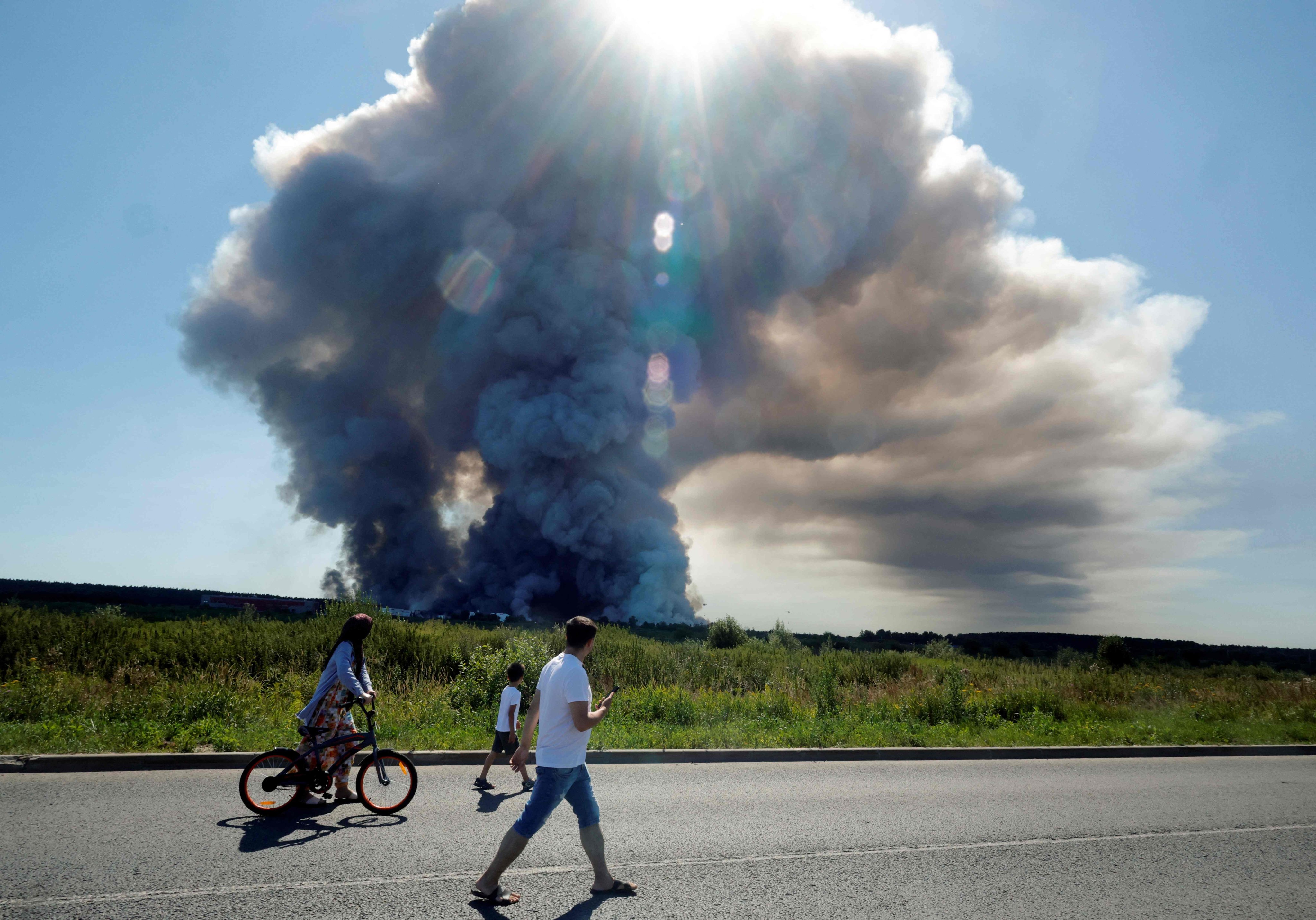 Residents walk past the smoke rising from Wildberries logistics complexes in the town of Elektrostal outside Moscow on Saturday. Photo: AFP