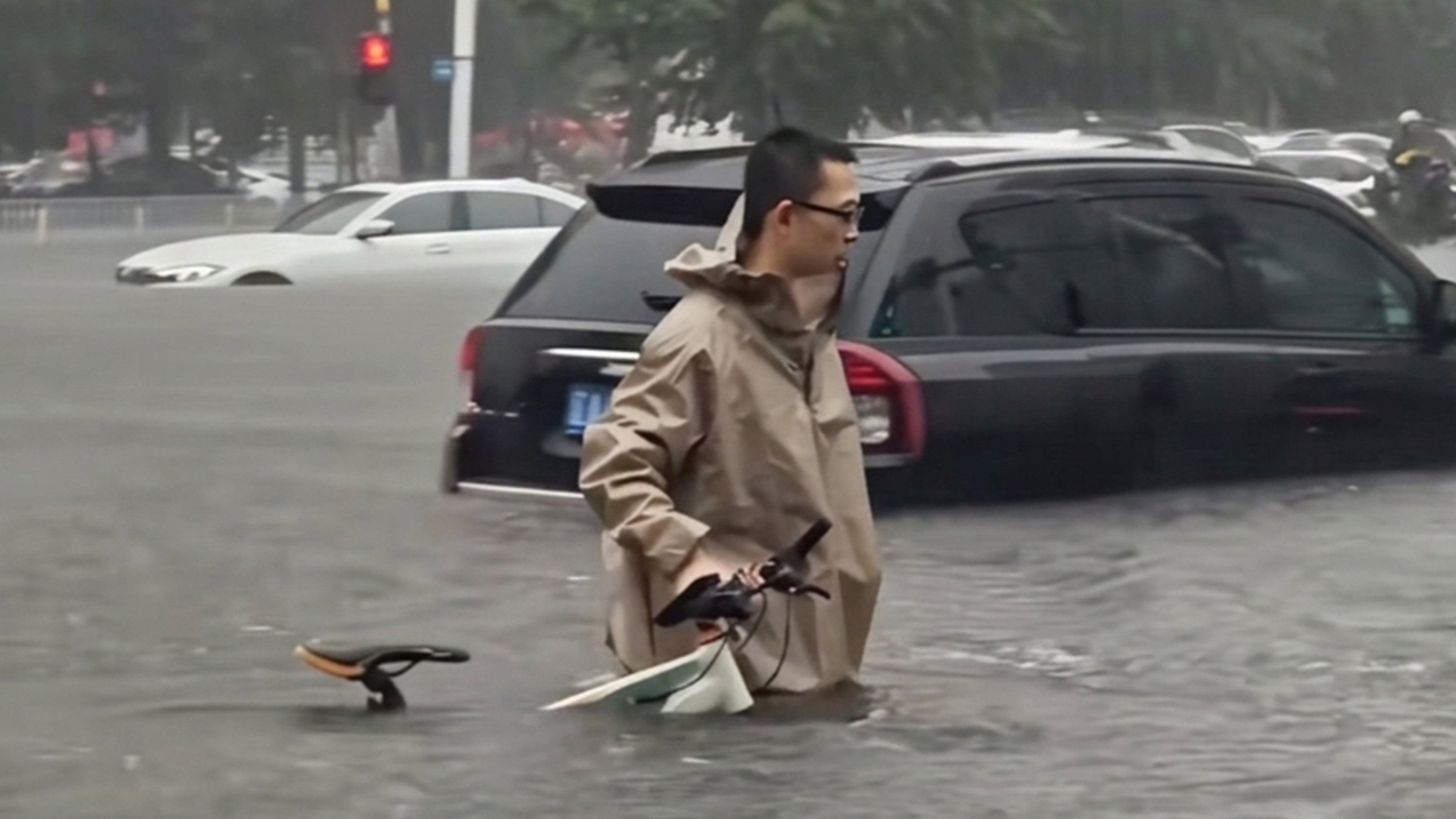 A man who went viral for wading through deep Shenyang floodwaters while pushing his bicycle was later revealed to be a surgeon racing to perform two critical operations. Photo: Douyin