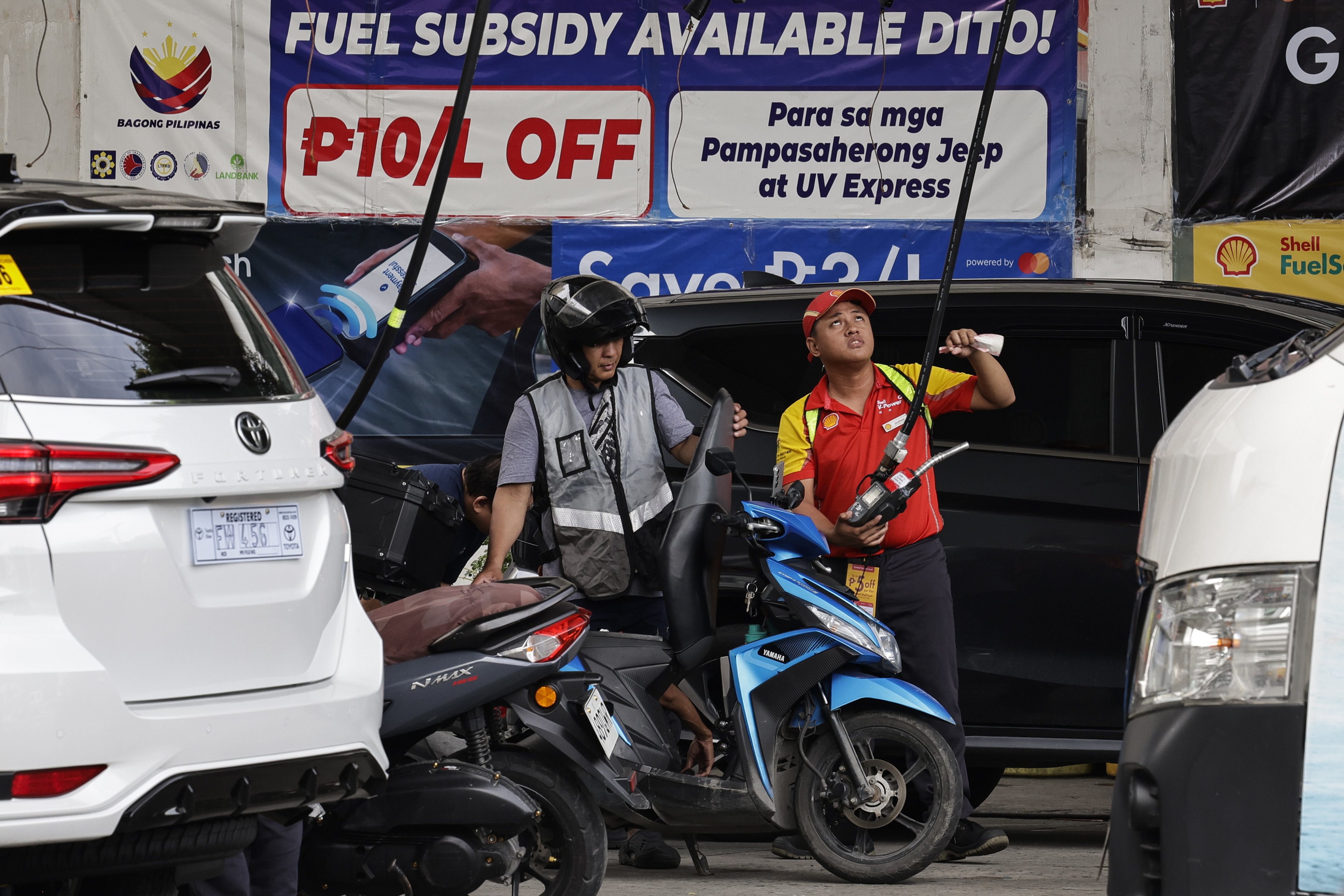 An attendant (right) refuels vehicles at a petrol station in Manila, the Philippines, on July 13. Photo: EPA