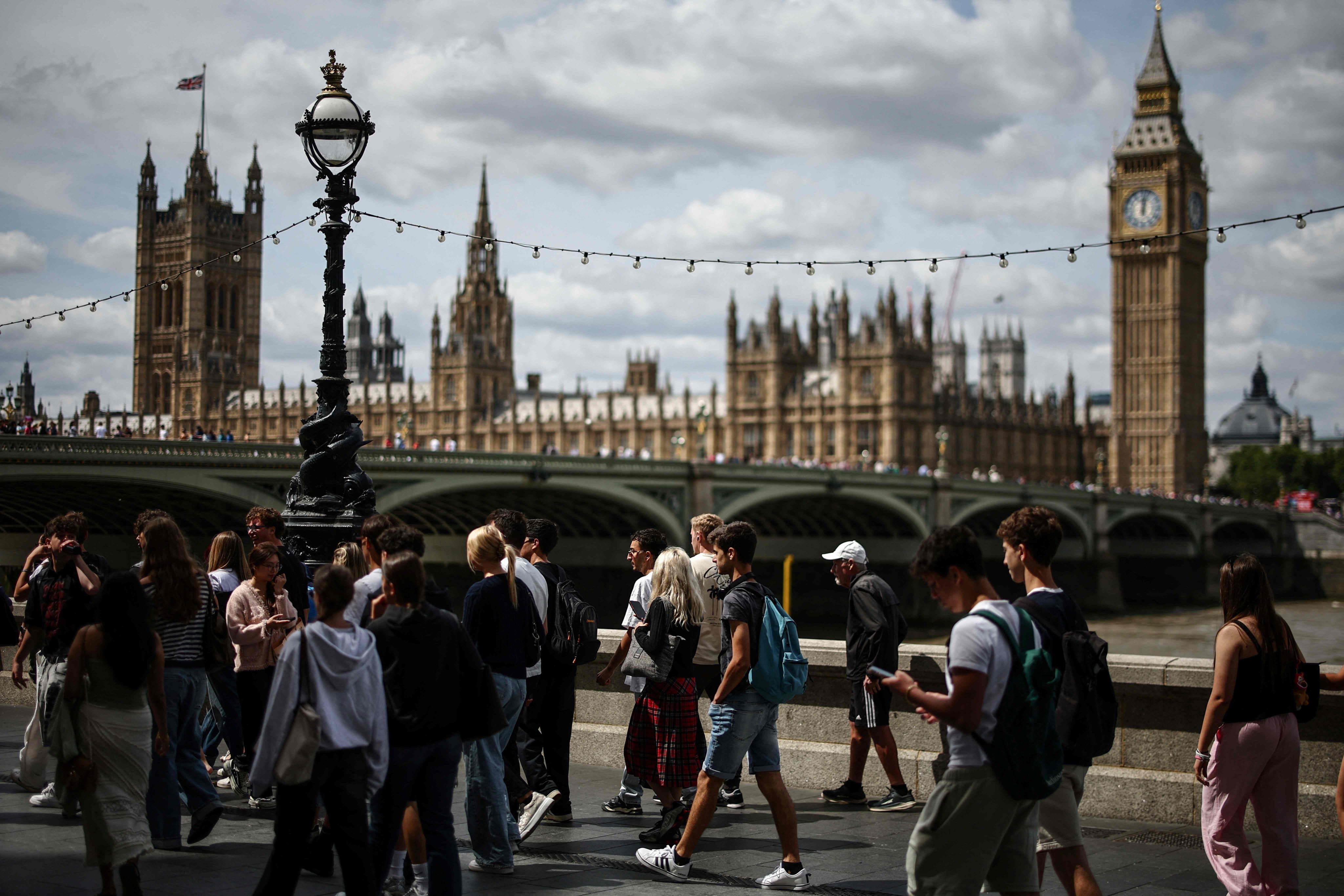 People walk along the South Bank of the River Thames near Parliament and Big Ben. Photo: AFP