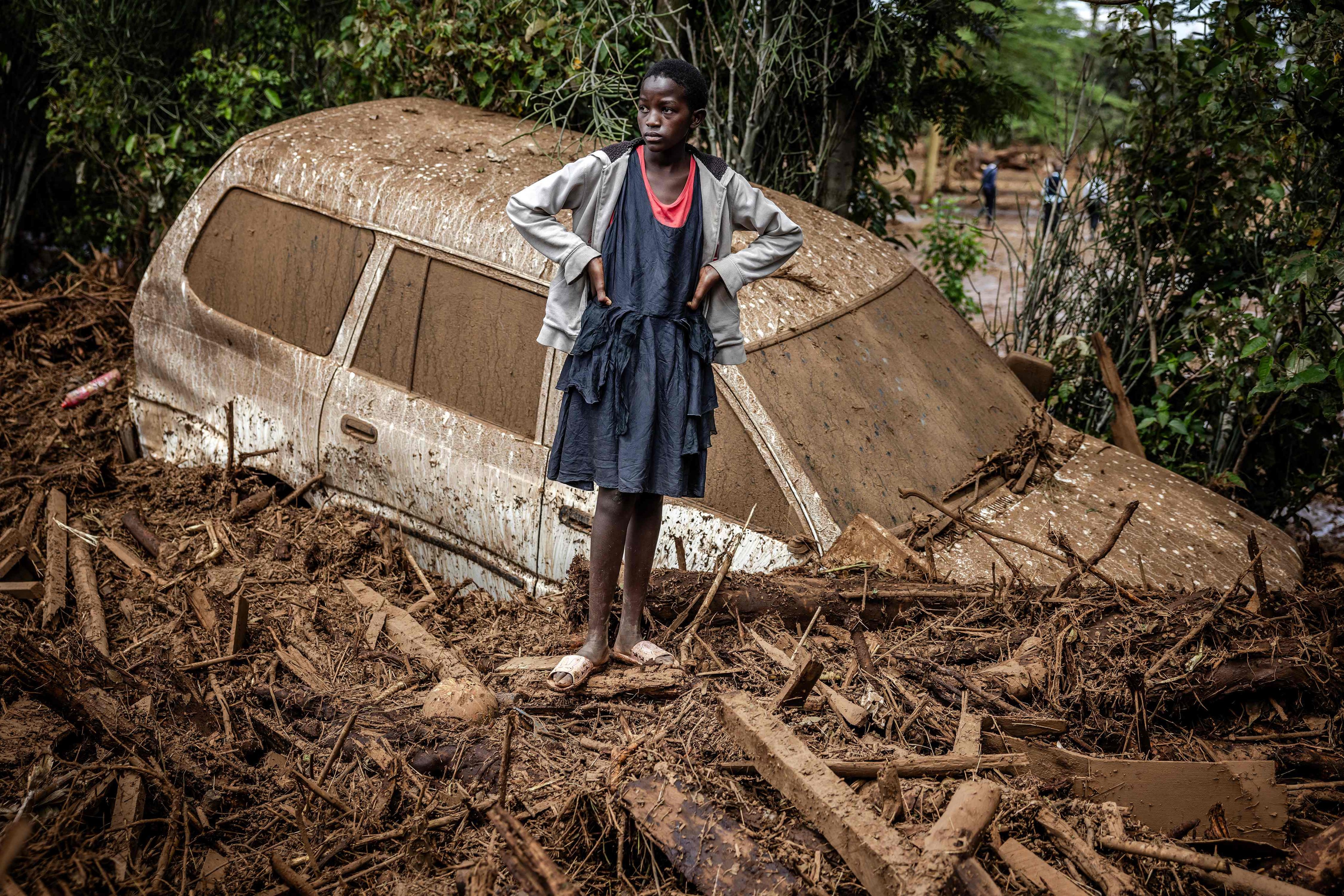 A girl looks on next to a damaged car buried in mud in an area heavily affected by torrential rains and flash floods in the village of Kamuchiri, Kenya, on April 29, 2024. In 2024, 120 people died in Kenya over the March-May wet season due to heavier than usual rainfall. Photo: AFP