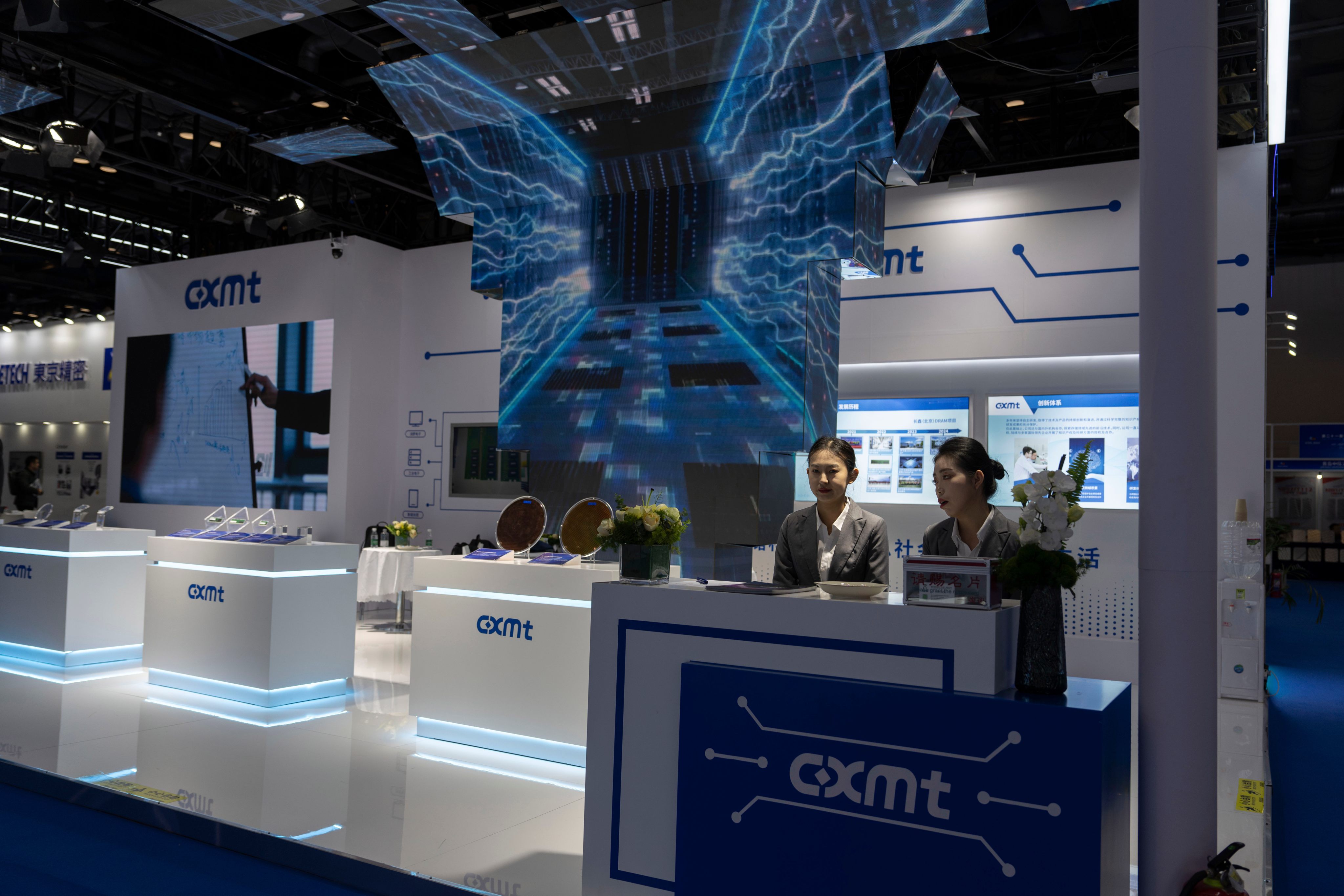 Workers at a booth for CXMT wait for visitors at the China International Semiconductor Expo in Beijing. Photo: AP