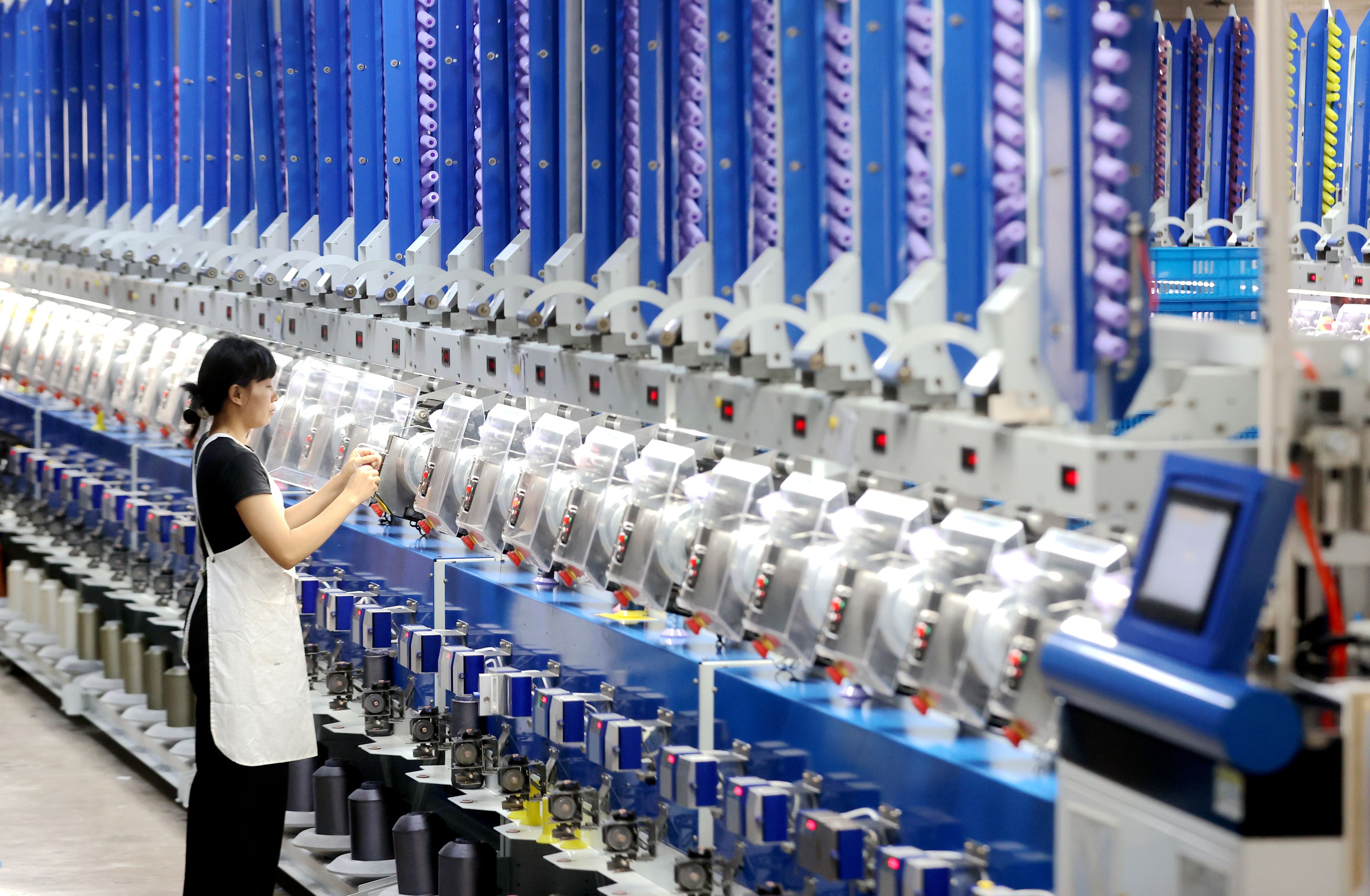 A worker checks automated spool winders at a factory in China’s Zhejiang province last month. A recent poll of private firms in the country found that many are still struggling. Photo: Xinhua