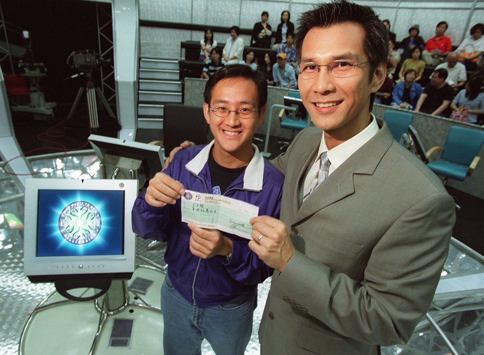 Ken Chan Kai-tai (right) , host of the television game show “Who wants to be a millionaire?” gives the cheque to Wong Man-cheung , the winner of HK$250,000 at the ATV Studio in Kowloon Tong on 15 May 2001.
