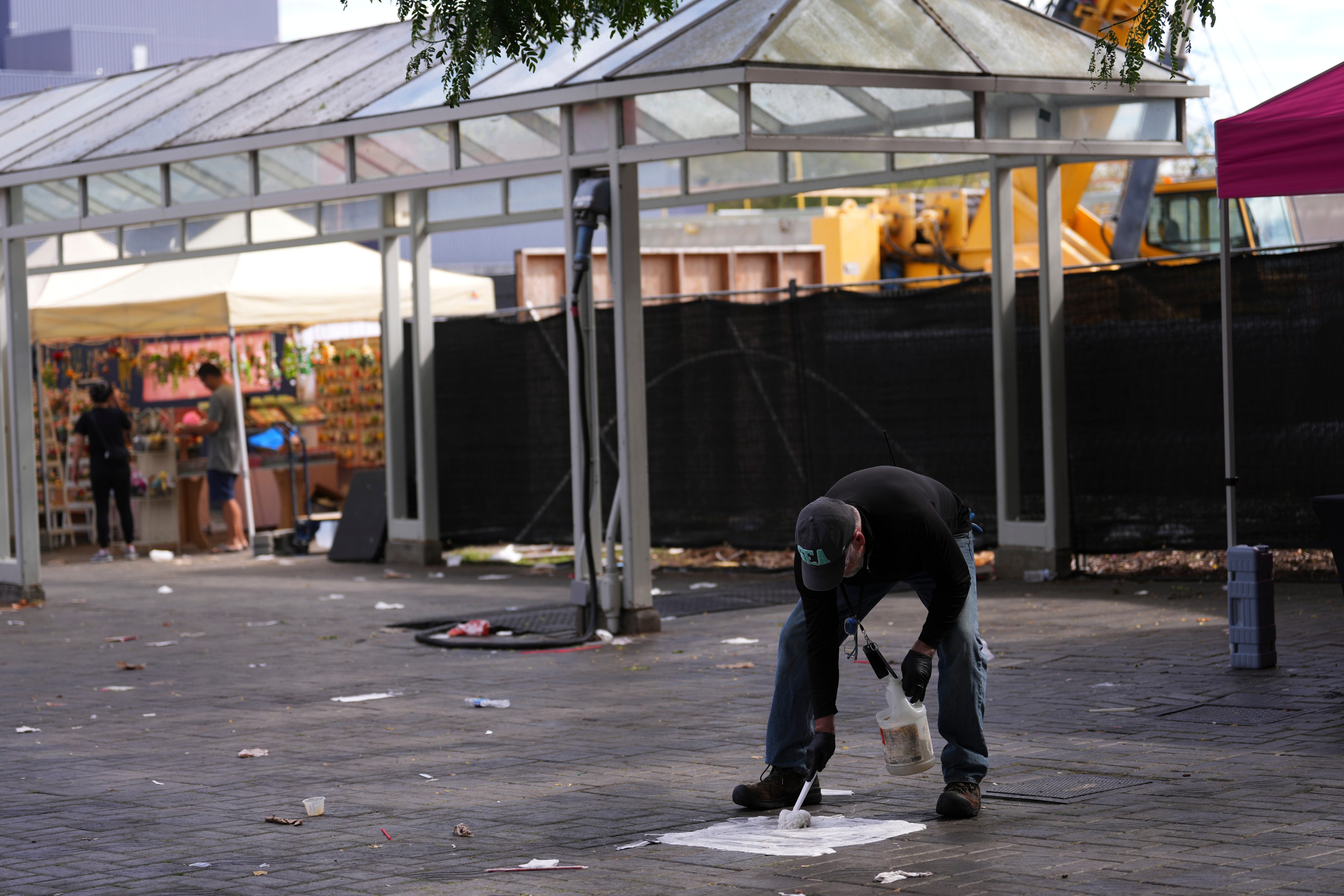 A worker cleans blood off the pavement on Monday, the day after a shooting at the Bite of Seattle food festival. Photo: AP