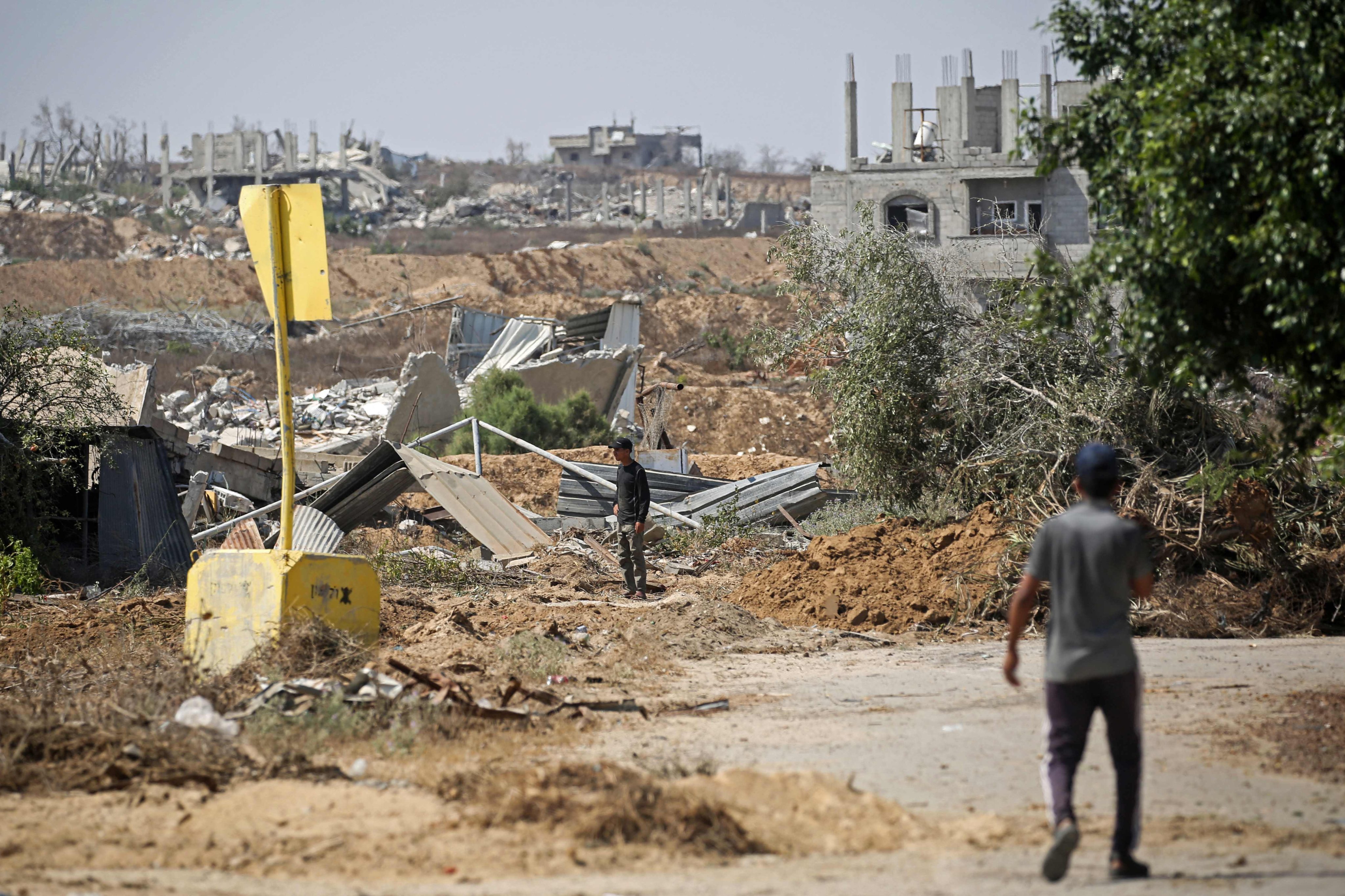 Palestinians walk past a concrete block marking the “yellow line” drawn by the Israeli military in the east of Deir al-Balah, central Gaza Strip on July 22. Photo: AFP