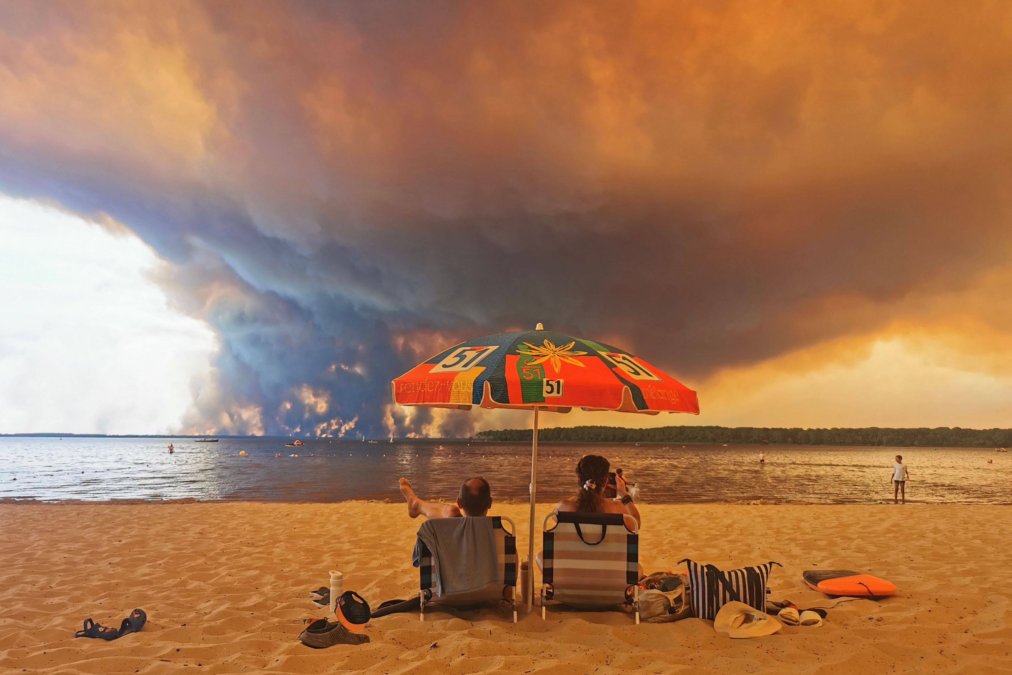 Beachgoers in Lacanau, southwestern France watch giant clouds of smoke rise into the sky from a wildfire. Photo: AFP