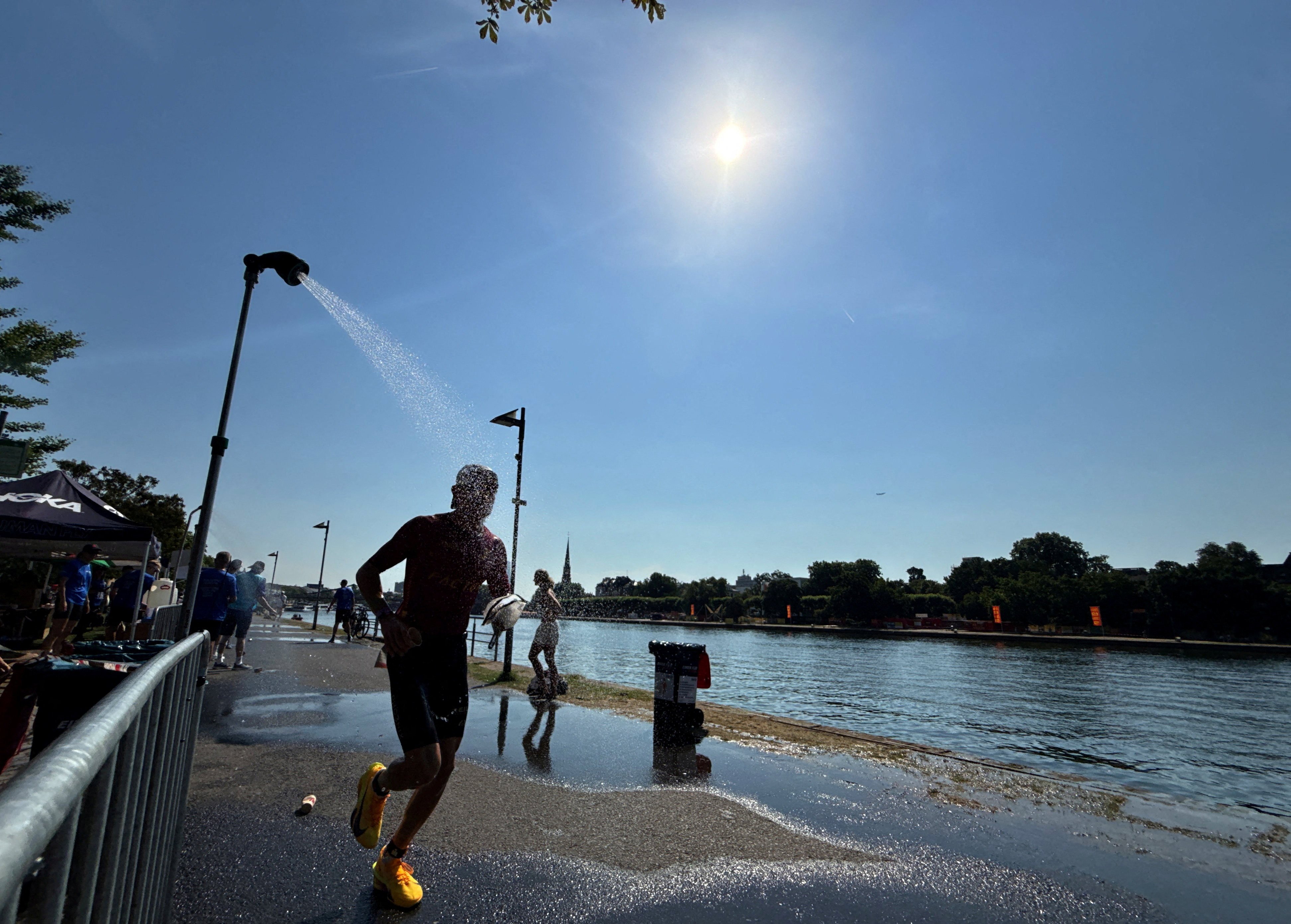 An athlete runs under a shower near the Main River to cool off during an ongoing heatwave in Frankfurt, Germany, on June 28. Photo: Reuters