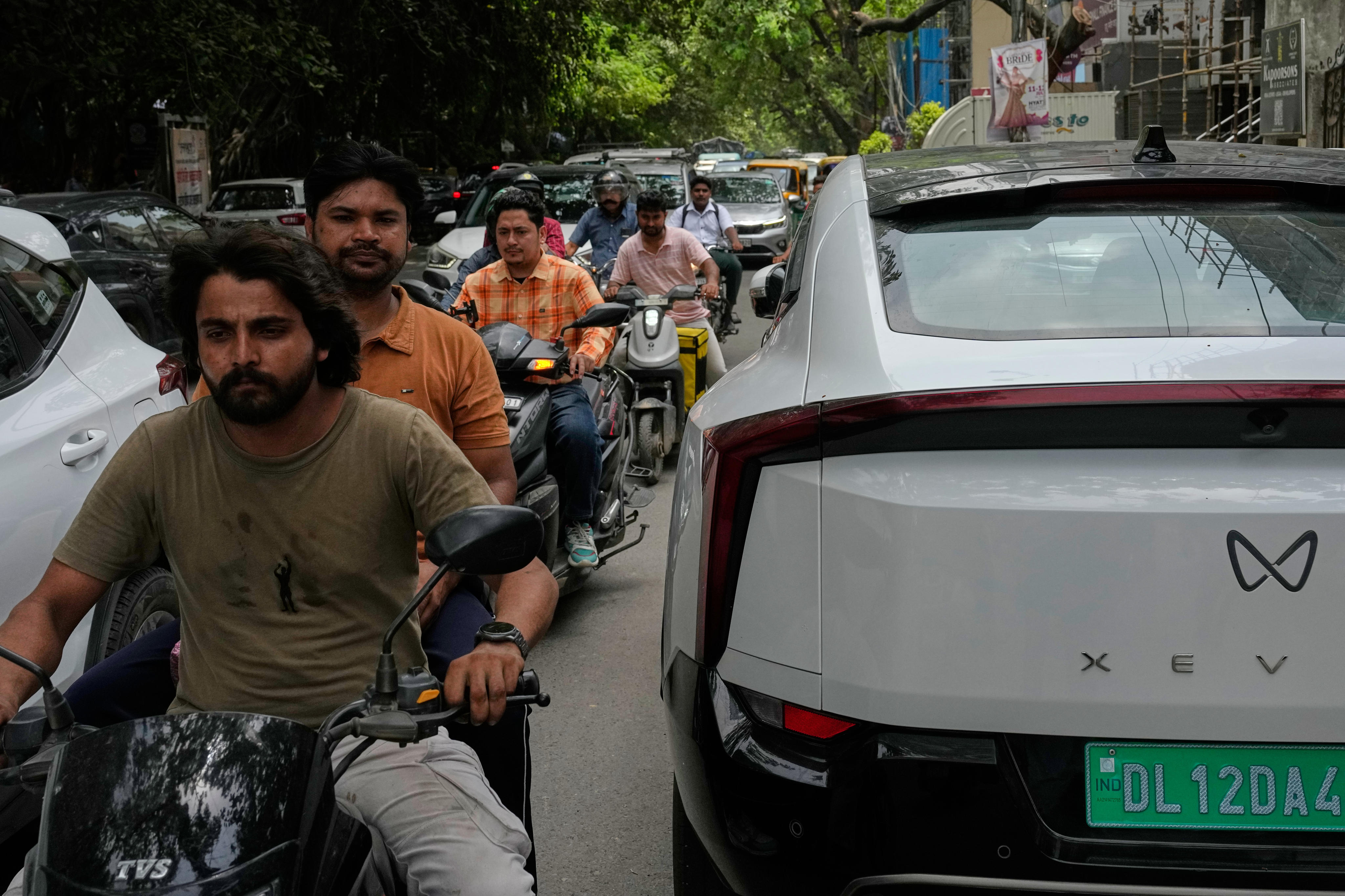 Motorcyclist ride past an electric vehicle parked on a Delhi street on July 13. Photo: AP