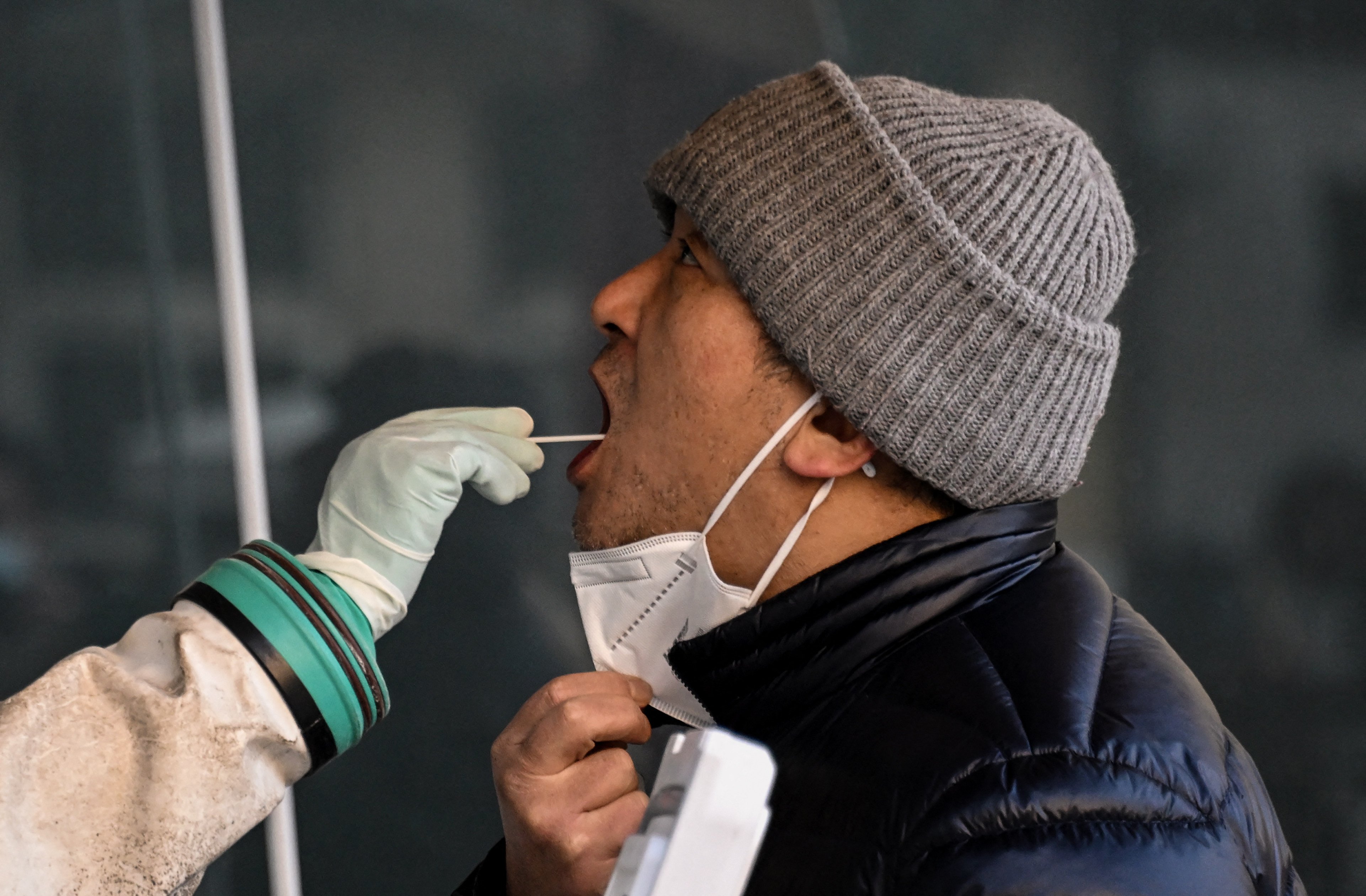 A health worker takes a swab sample from a man to be tested for the Covid-19 coronavirus at a hospital in Beijing on December 26, 2022. (Photo by Noel CELIS / AFP)
