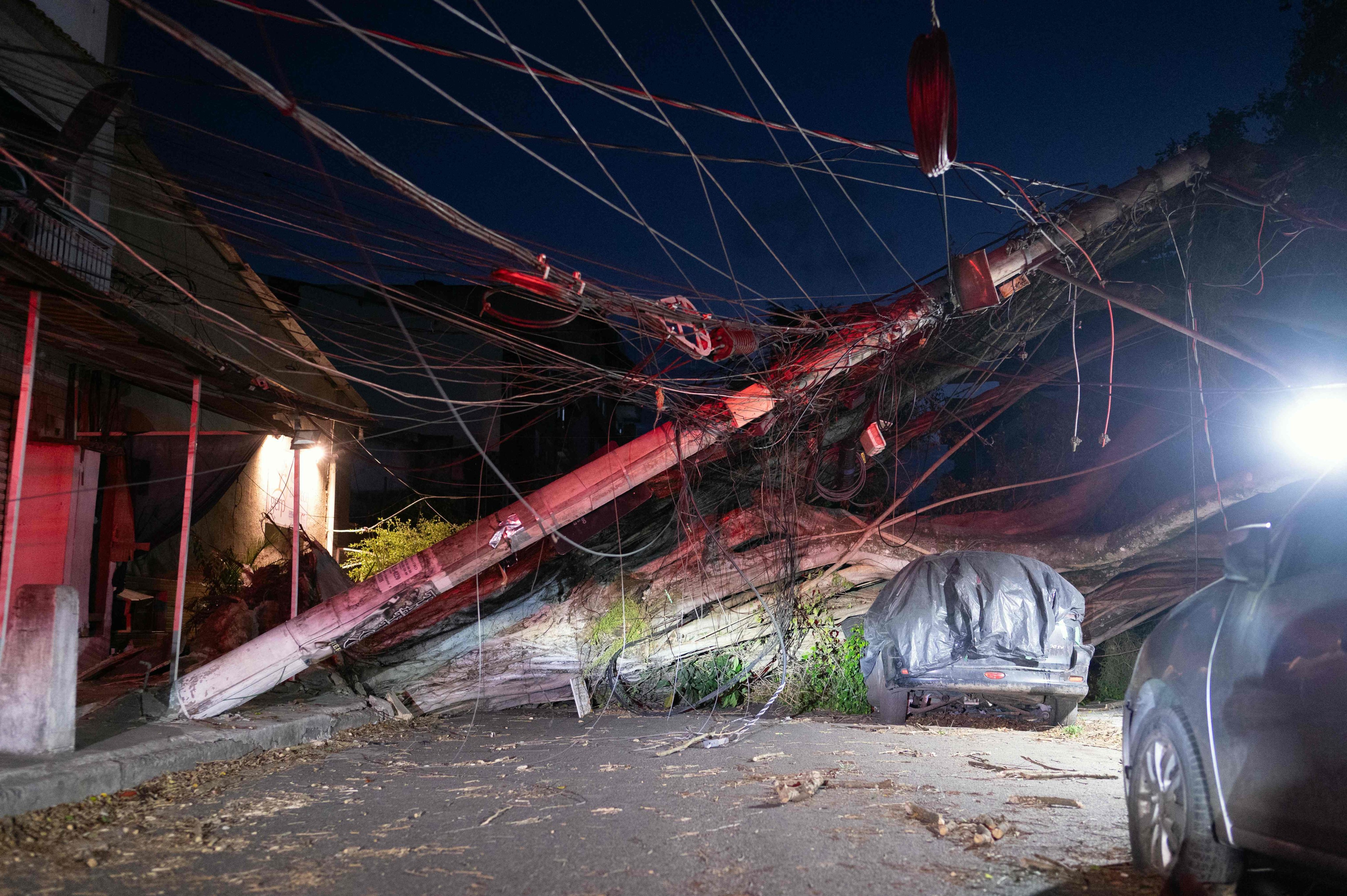 A fallen tree and collapsed utility poles block a residential street after strong wind gusts in Rio de Janeiro, Brazil, on Wednesday. Photo: AFP