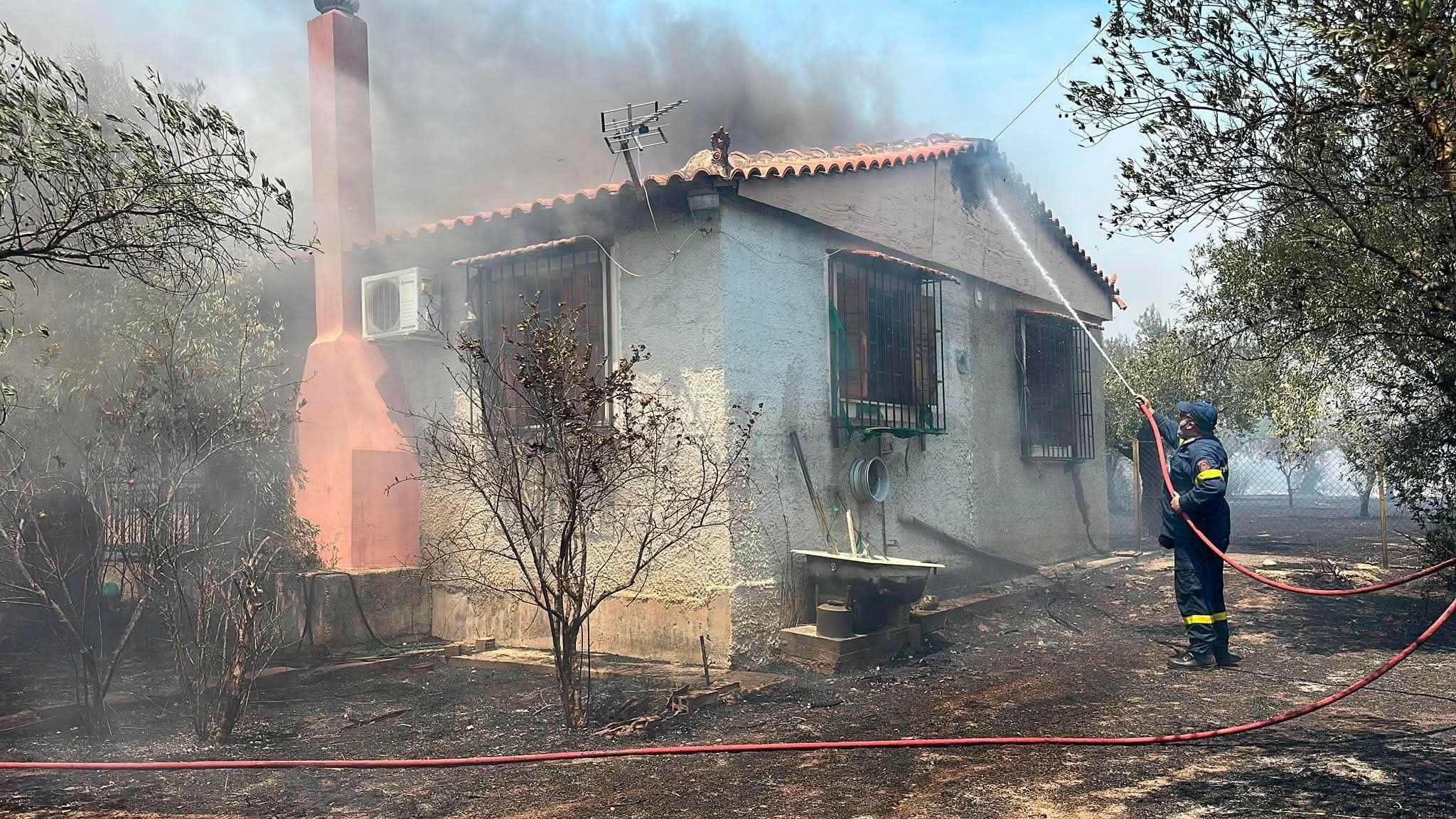 Firefighters battle a wildfire threatening to engulf a house in the Peloponnese region of Greece on Friday. Photo: EPA