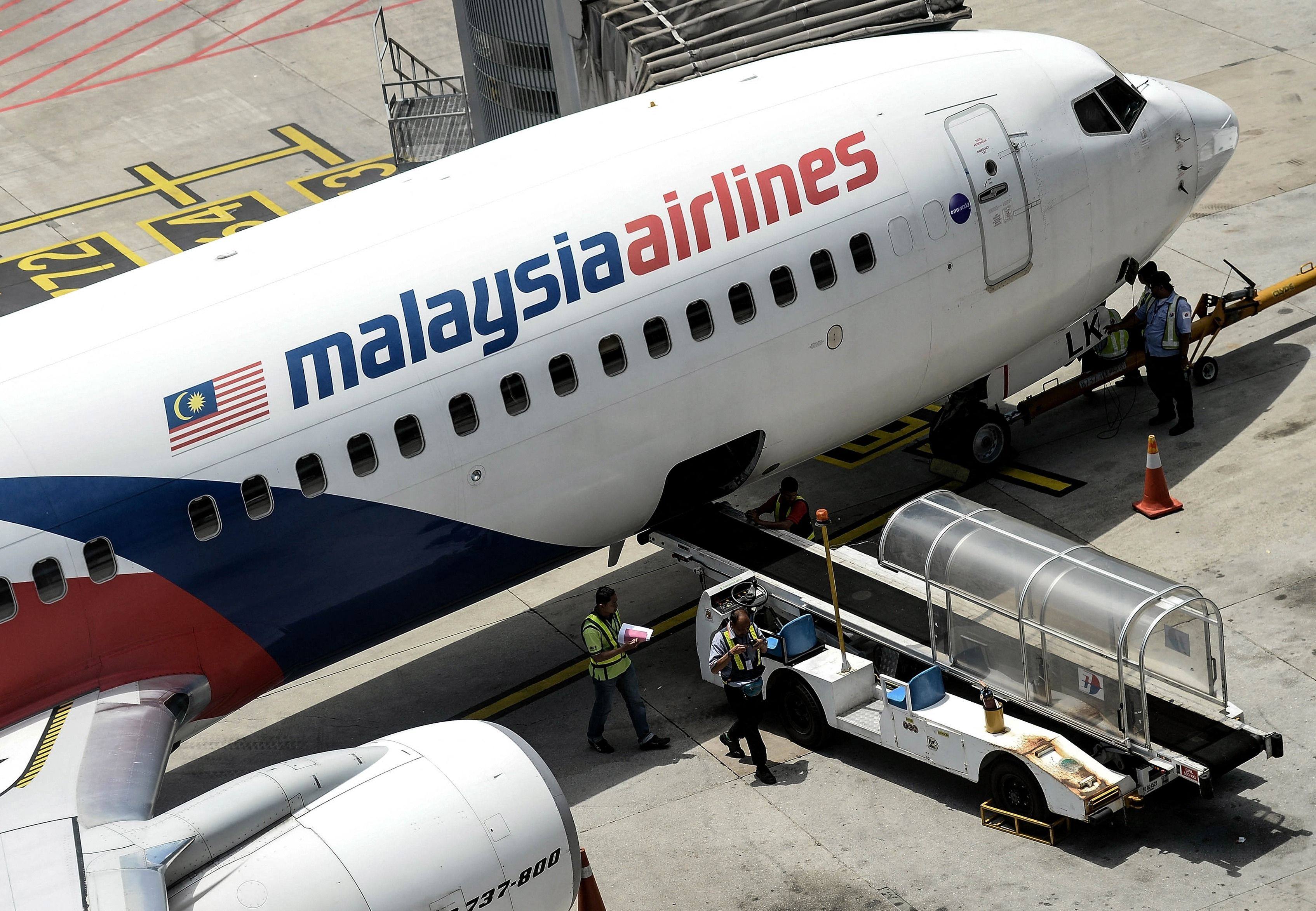 Malaysia Airlines ground staff walk on the tarmac next to a Malaysia Airlines plane at Kuala Lumpur International Airport. Photo: AFP