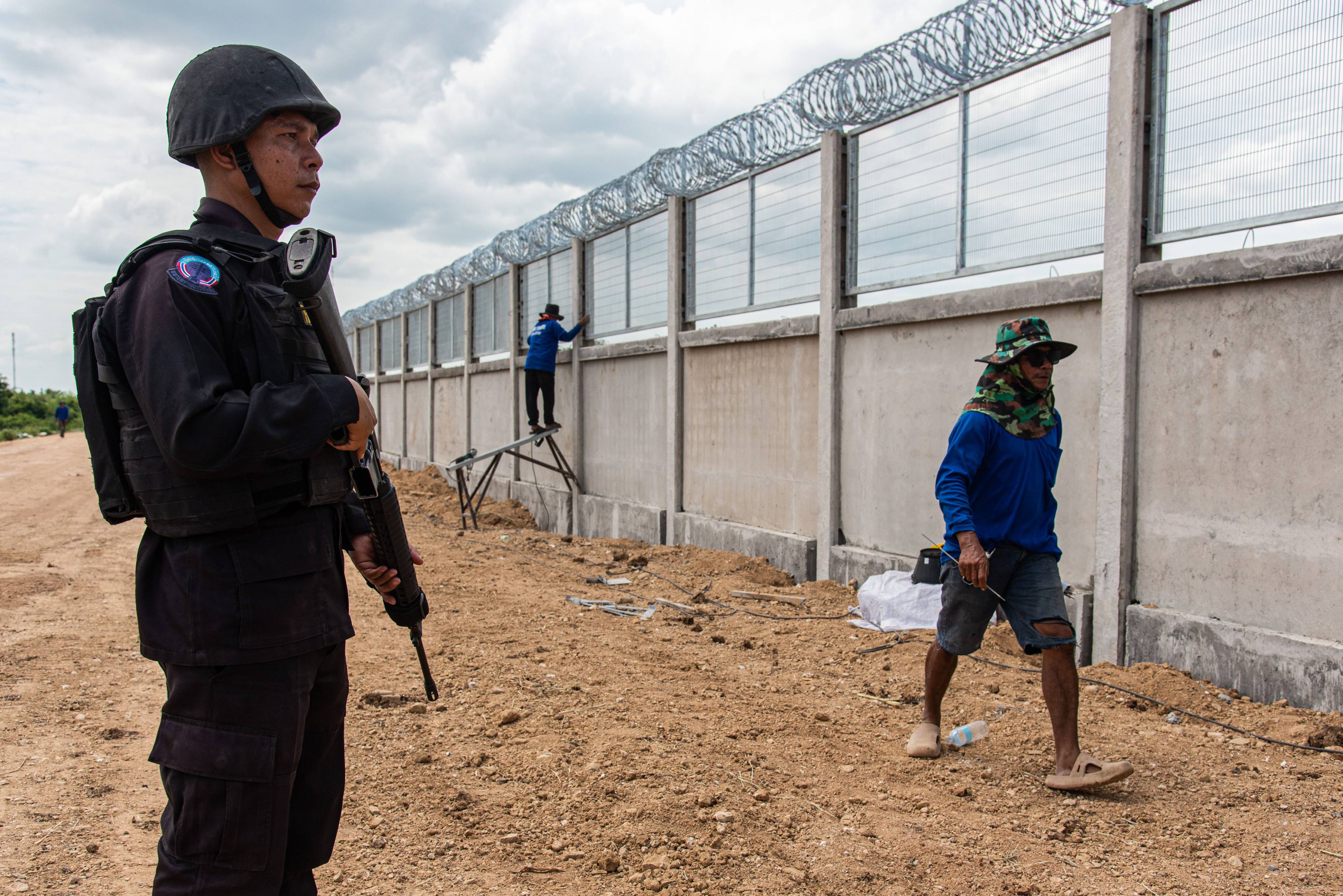 A Thai soldier stands guard while workers in the Pong Nam Ron district of Chanthaburi erect a section of the border fence between Thailand and Cambodia. Photo: SOPA Images
