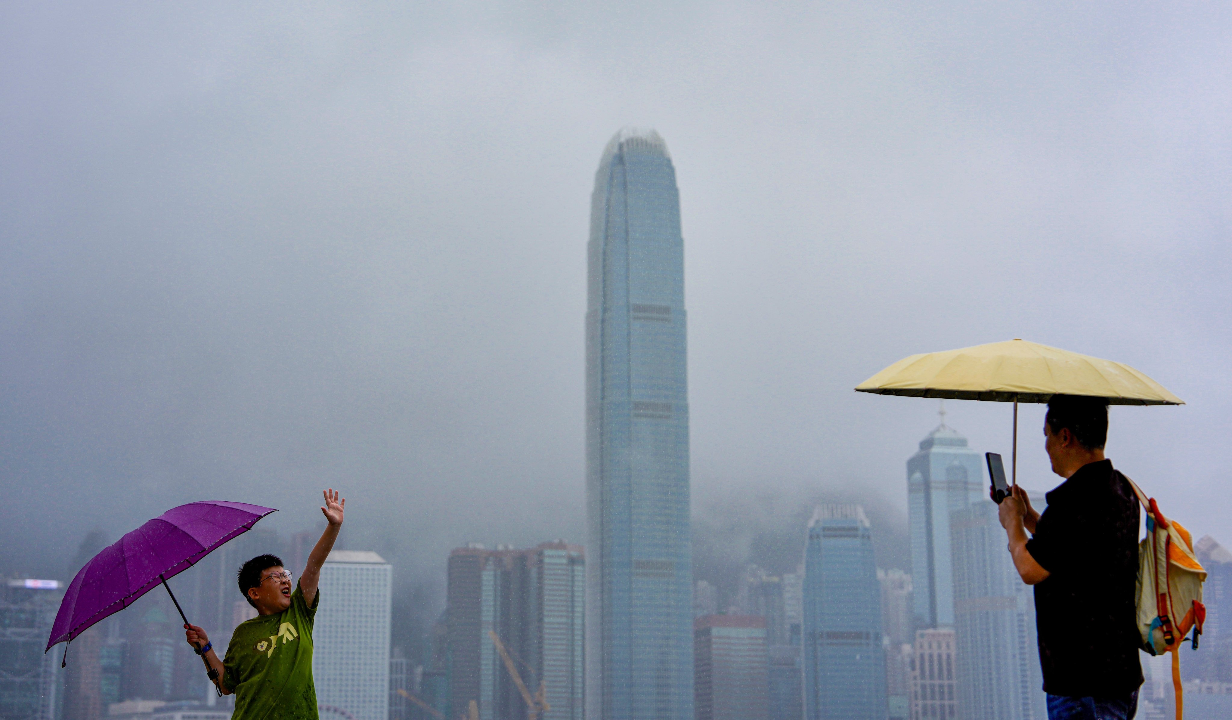 Tourists brave the wind and rain at the Tsim Sha Tsui waterfront. Photo: Sam Tsang
