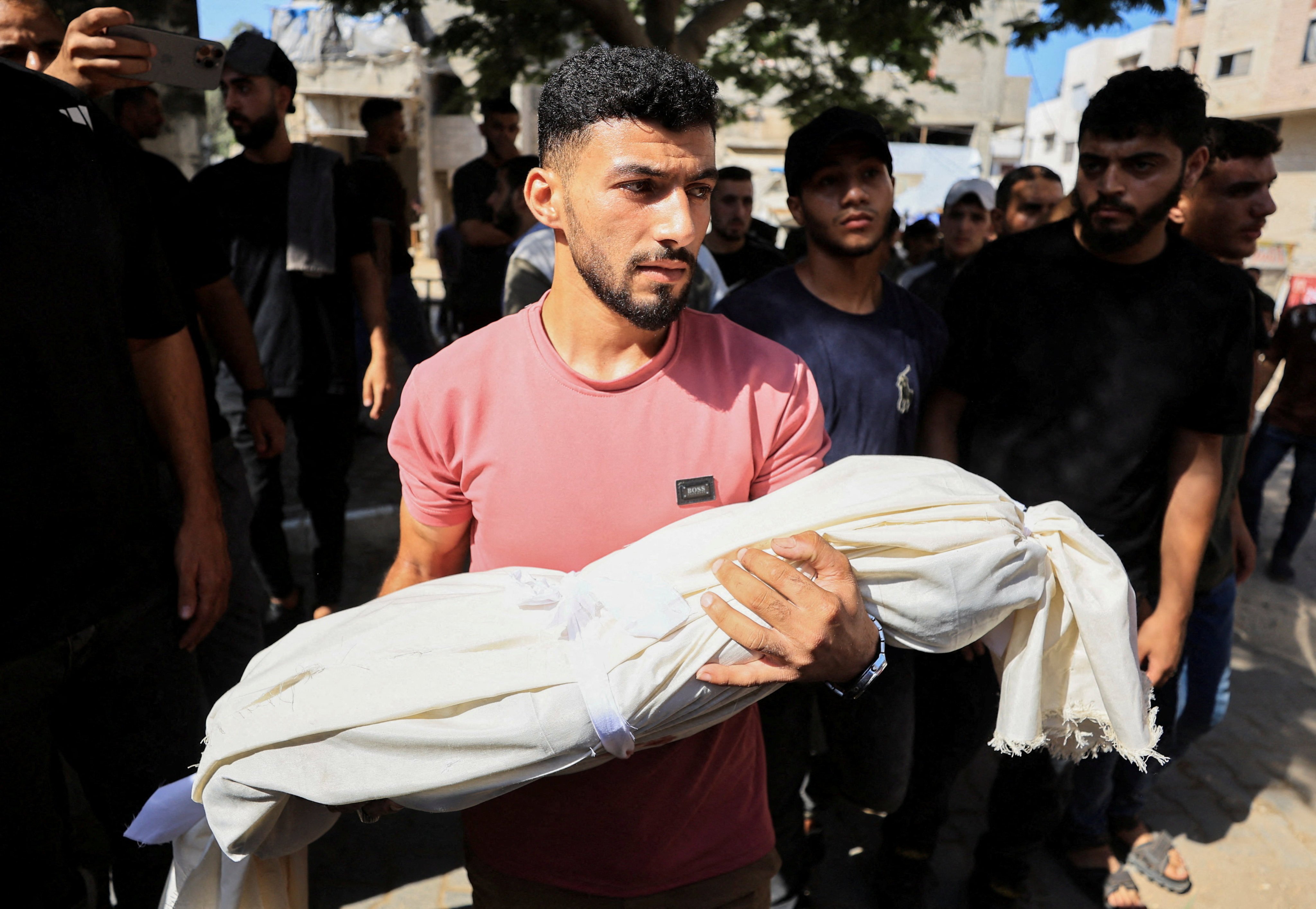 A young man in Gaza City on Sunday carries the body of a child killed in Israeli strikes, according to medics. Photo: Reuters