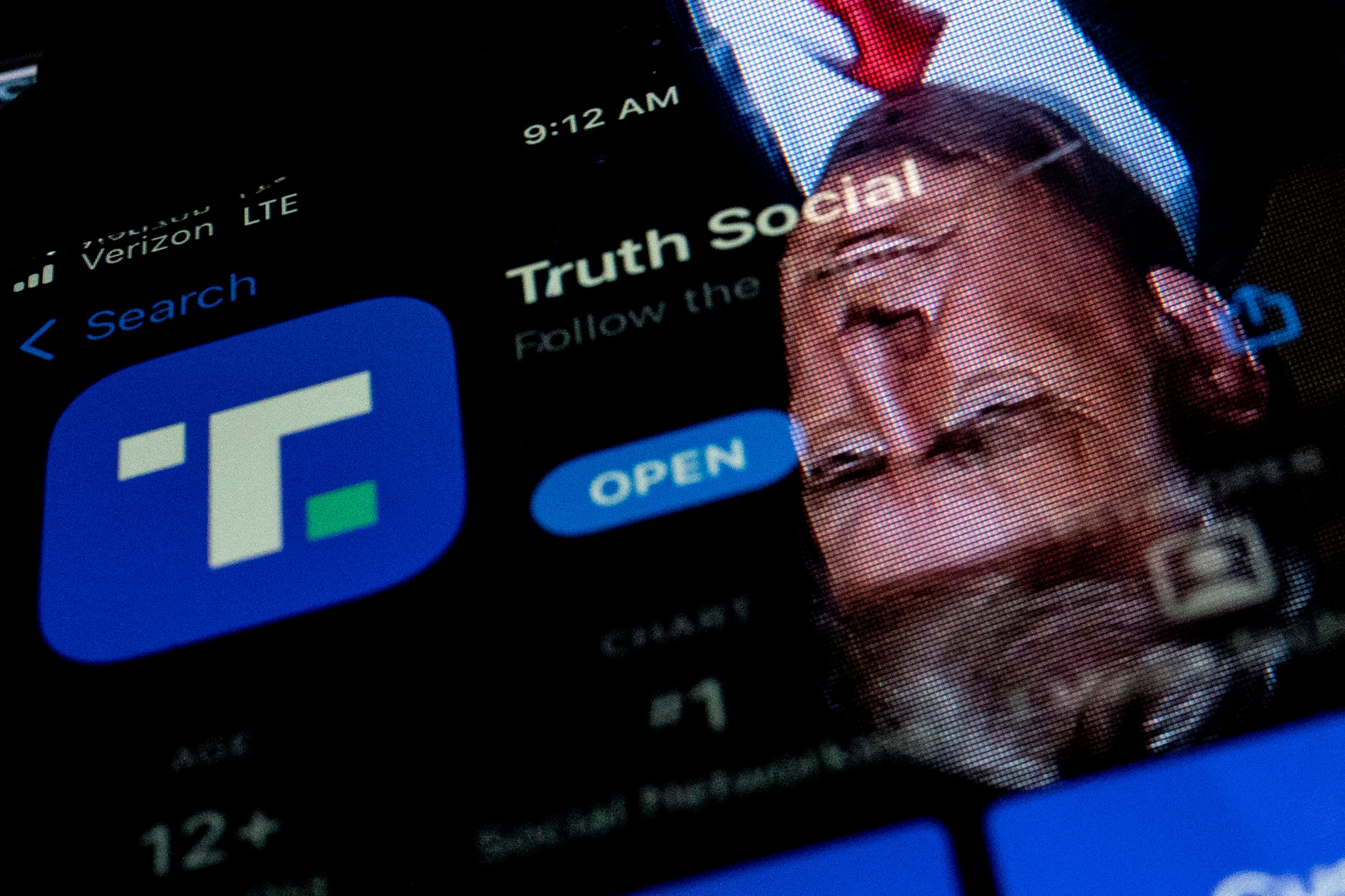 President Donald Trump reflected in a phone screen displaying the Truth Social app. Photo: TNS