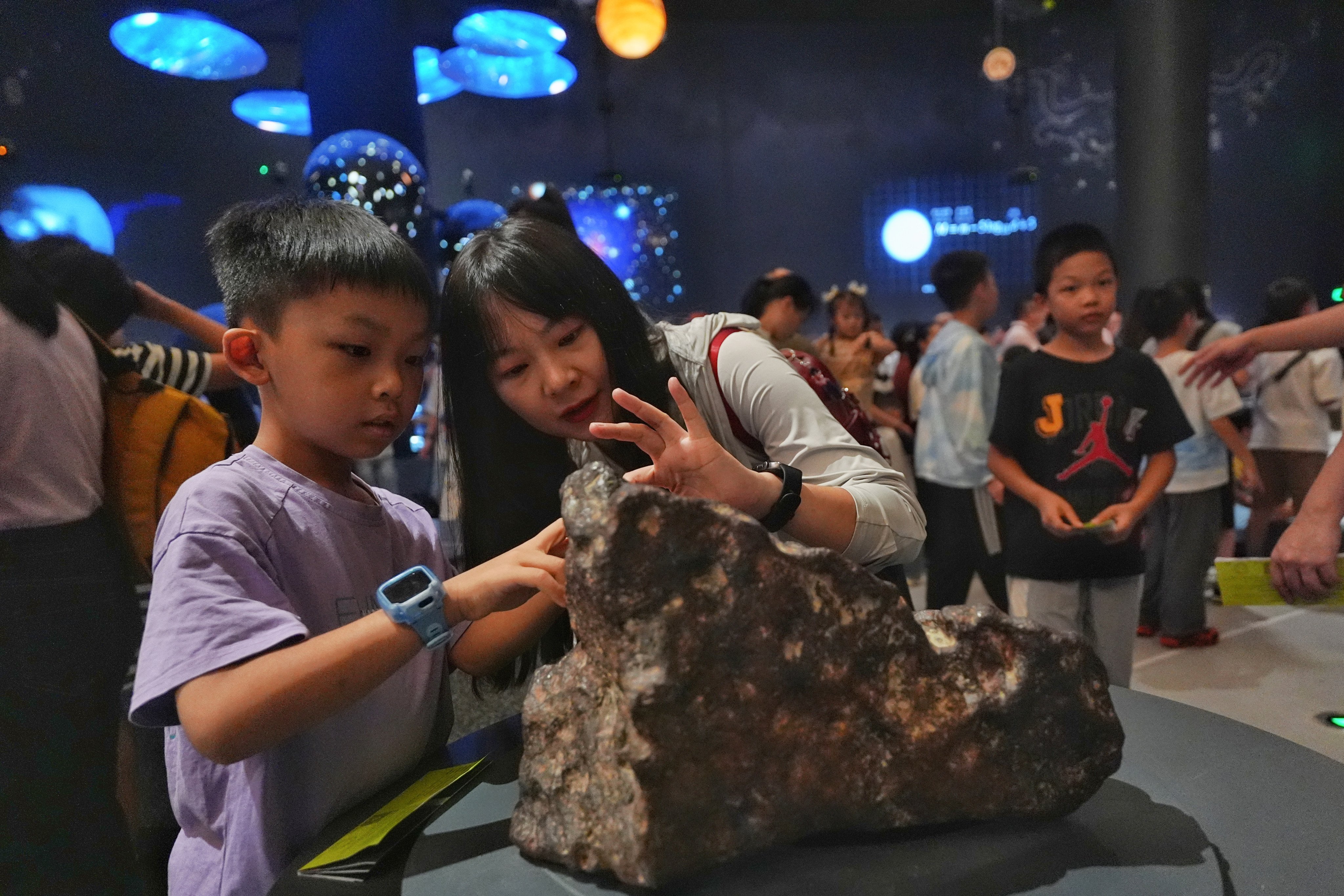 Visitors touch a meteorite displayed at the Cosmos Hall in the Shenzhen Natural History Museum. Photo: Elson Li