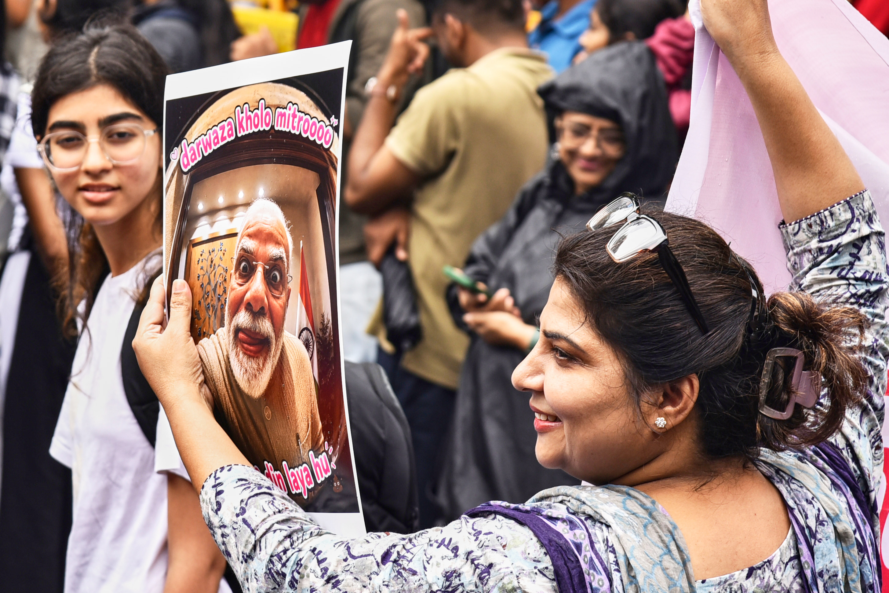 A protestor holds a placard portraying Indian Prime Minister Narendra Modi with text saying: “Open the door, friends, I bring bad times” on July 24. Photo: AP