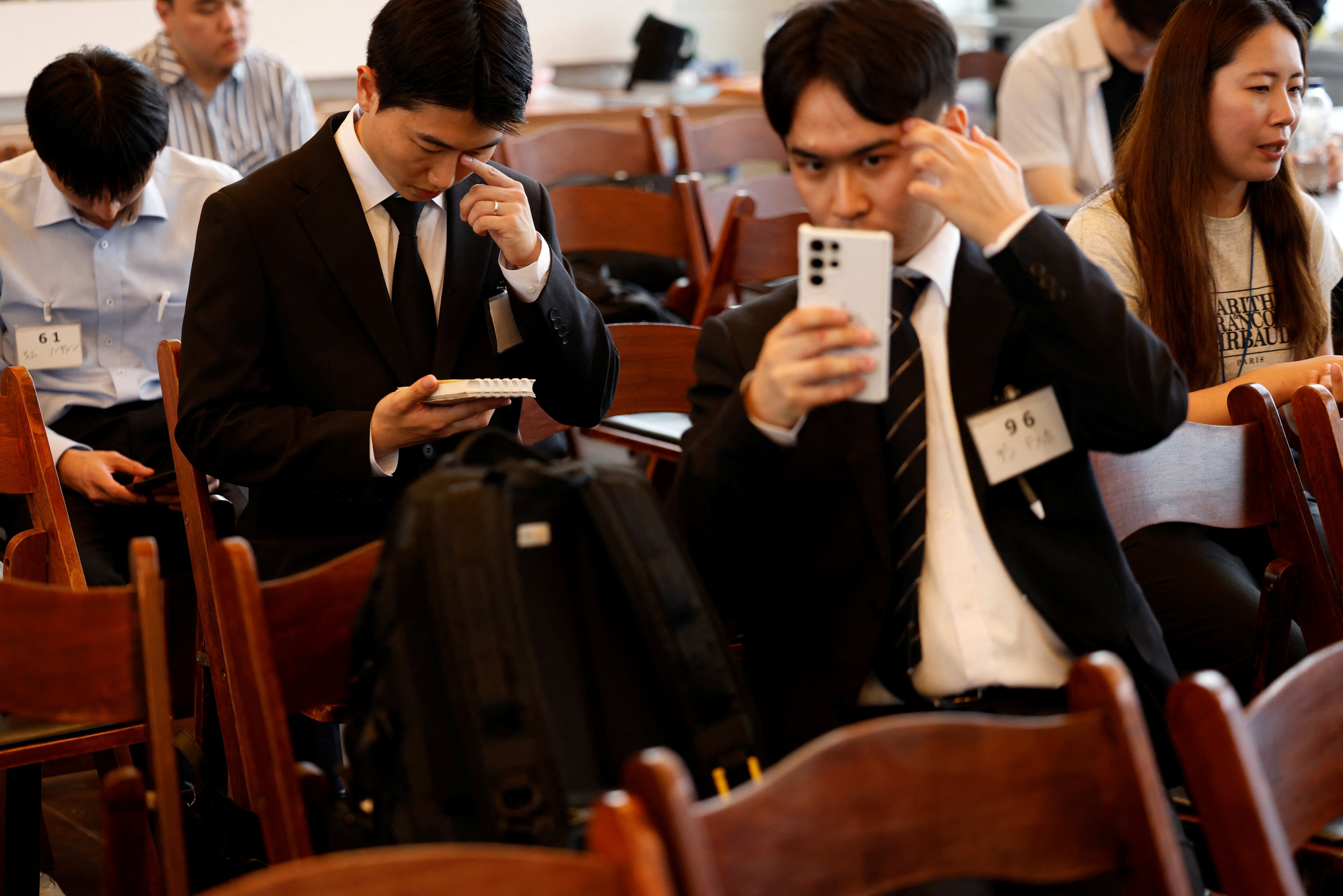 A South Korean applicant checks his appearance using a smartphone as another reviews his notes before an interview at a job fair in Seoul on July 12. Photo: Reuters