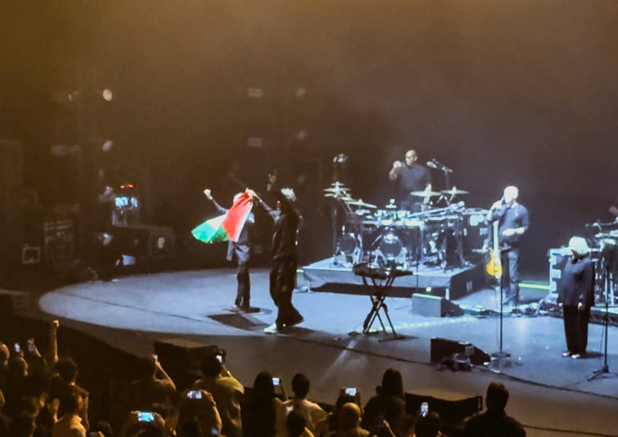 Robert Del Naja and Grant Marshall from Massive Attack stand with a Palestinian flag onstage at the end of their performance in Singapore on Wednesday. Photo: Social media/Reuters
