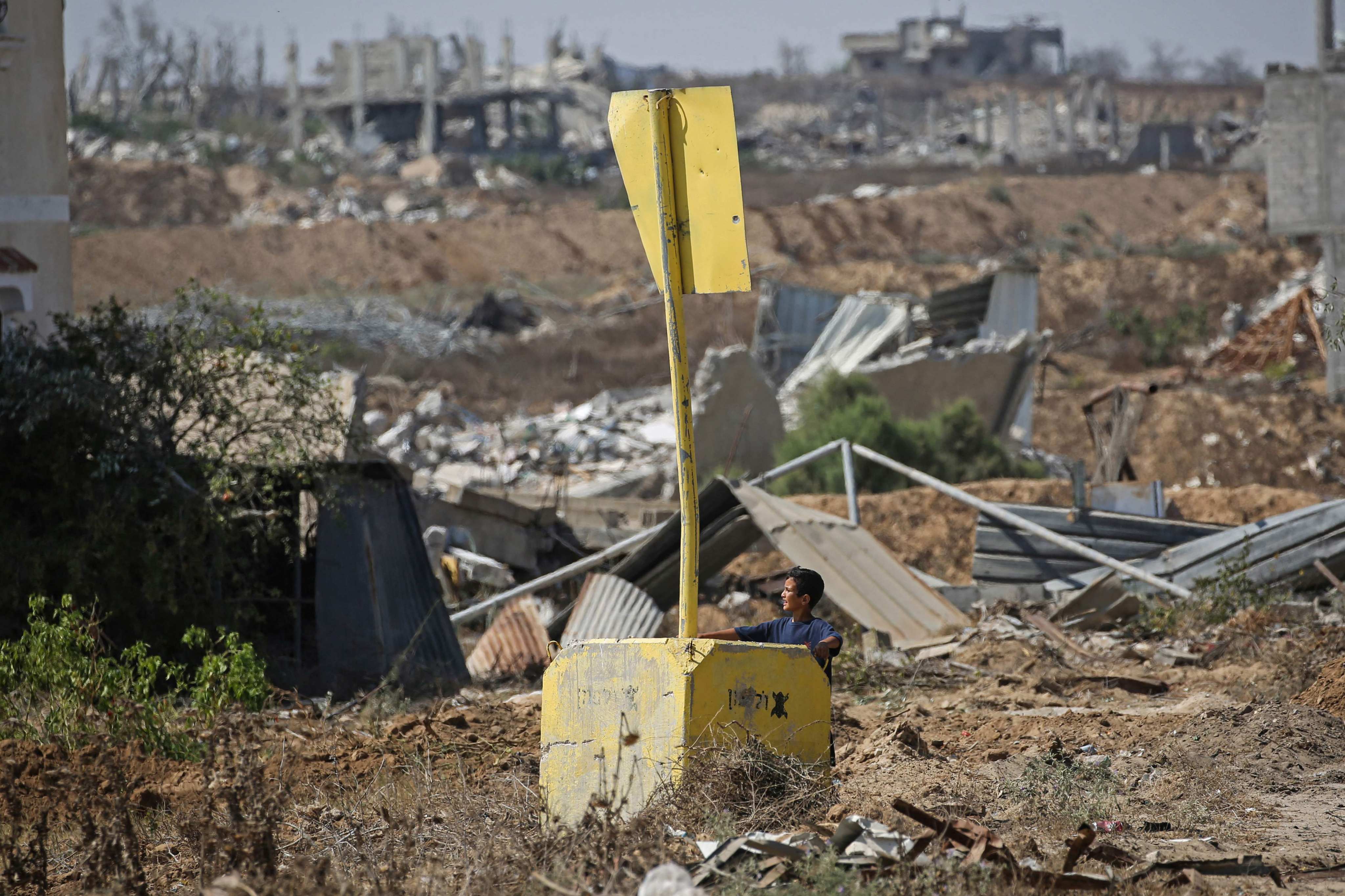 A Palestinian boy stands beside a marker designating the 'Yellow Line' set by the Israeli military in Deir al-Balah, central Gaza Strip. Photo: AFP