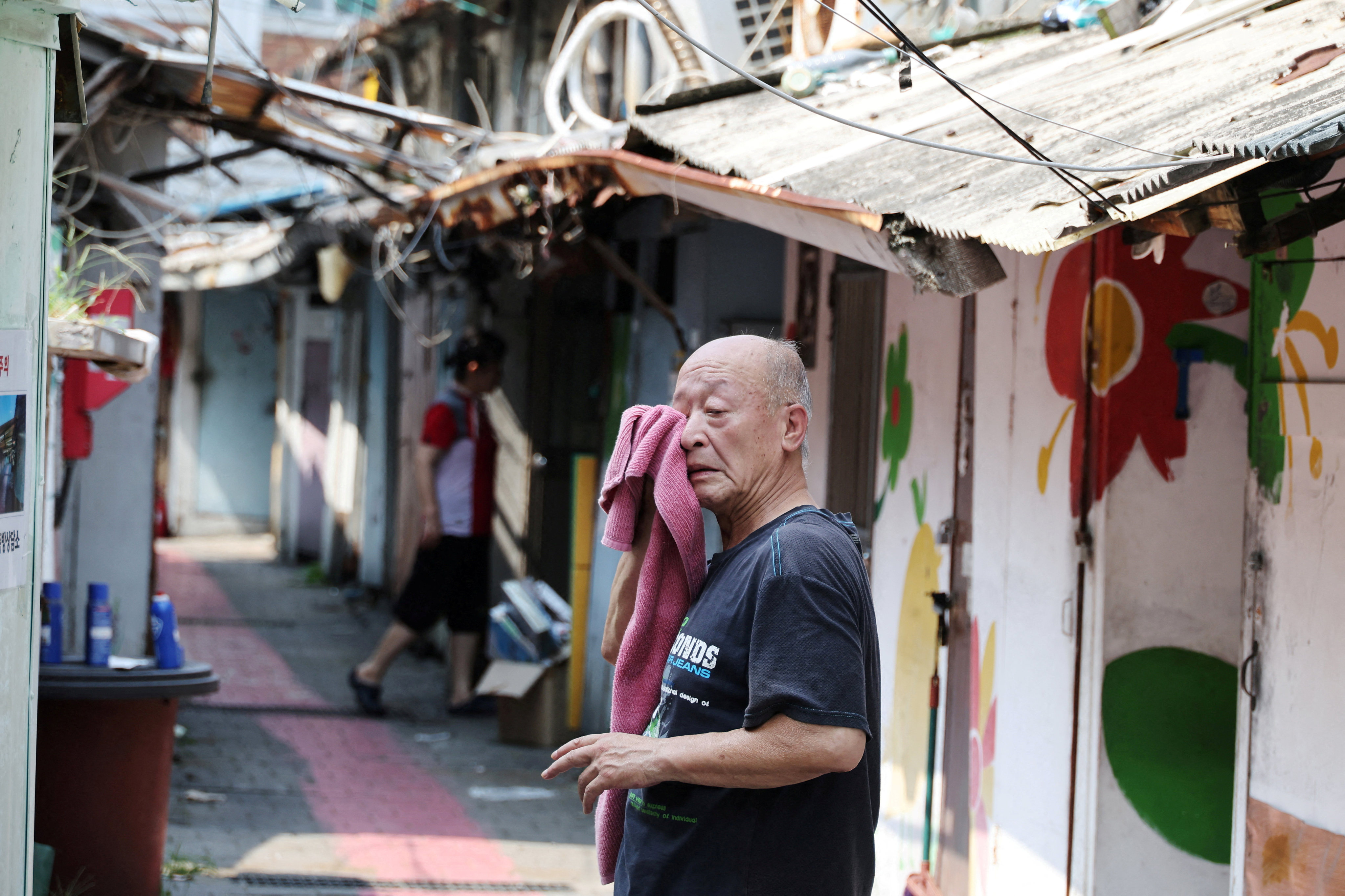 A man wipes off sweat at a jjokbang village which is a tiny single-room housing district, during the first-ever severe heatwave warning in Seoul, South Korea, August 4, 2026.   REUTERS/Kim Hong-Ji