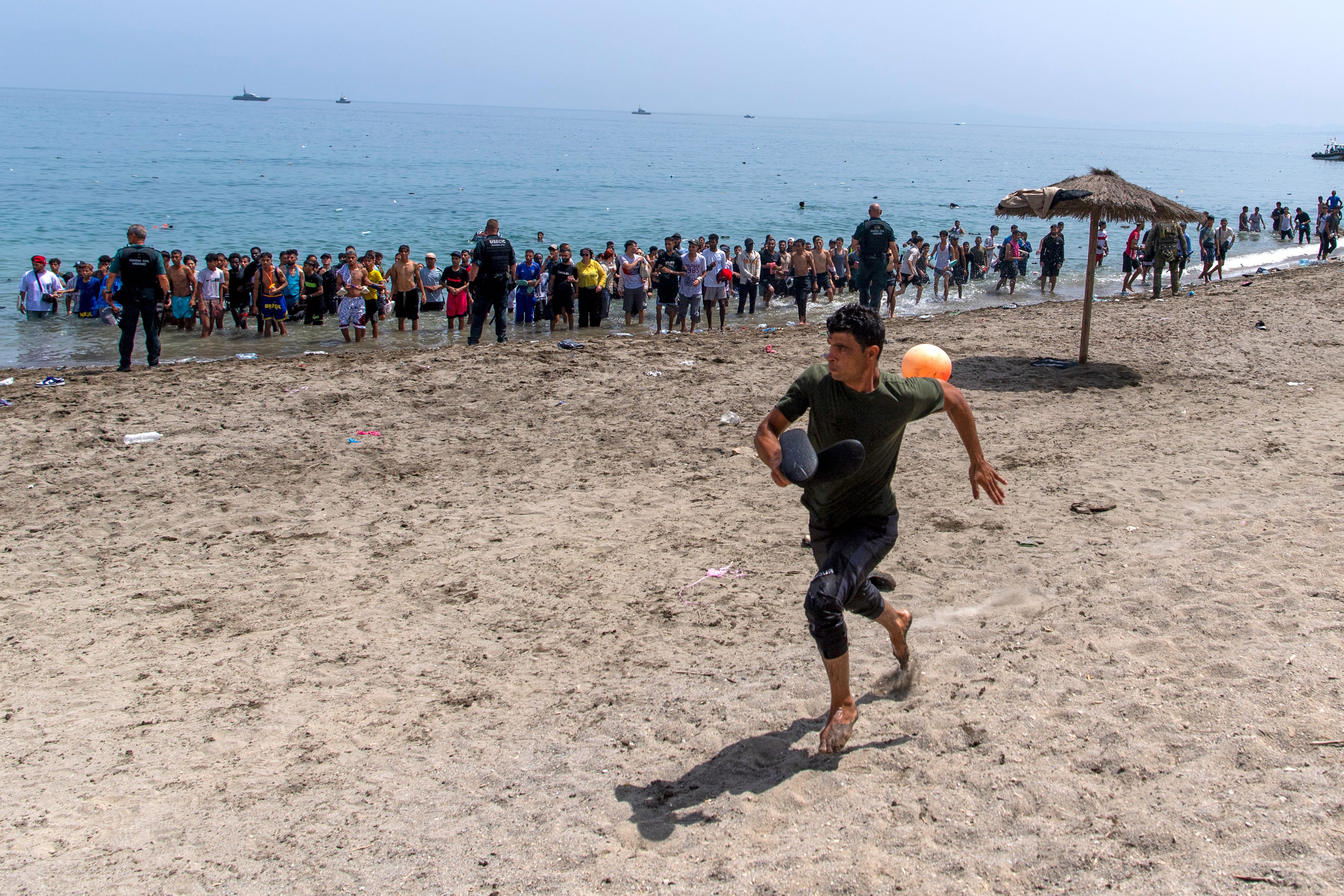 A migrant runs from Spanish police as they cordon off access to the beach for people crossing from Morocco into the Spanish enclave of Ceuta on Friday. Photo: AP