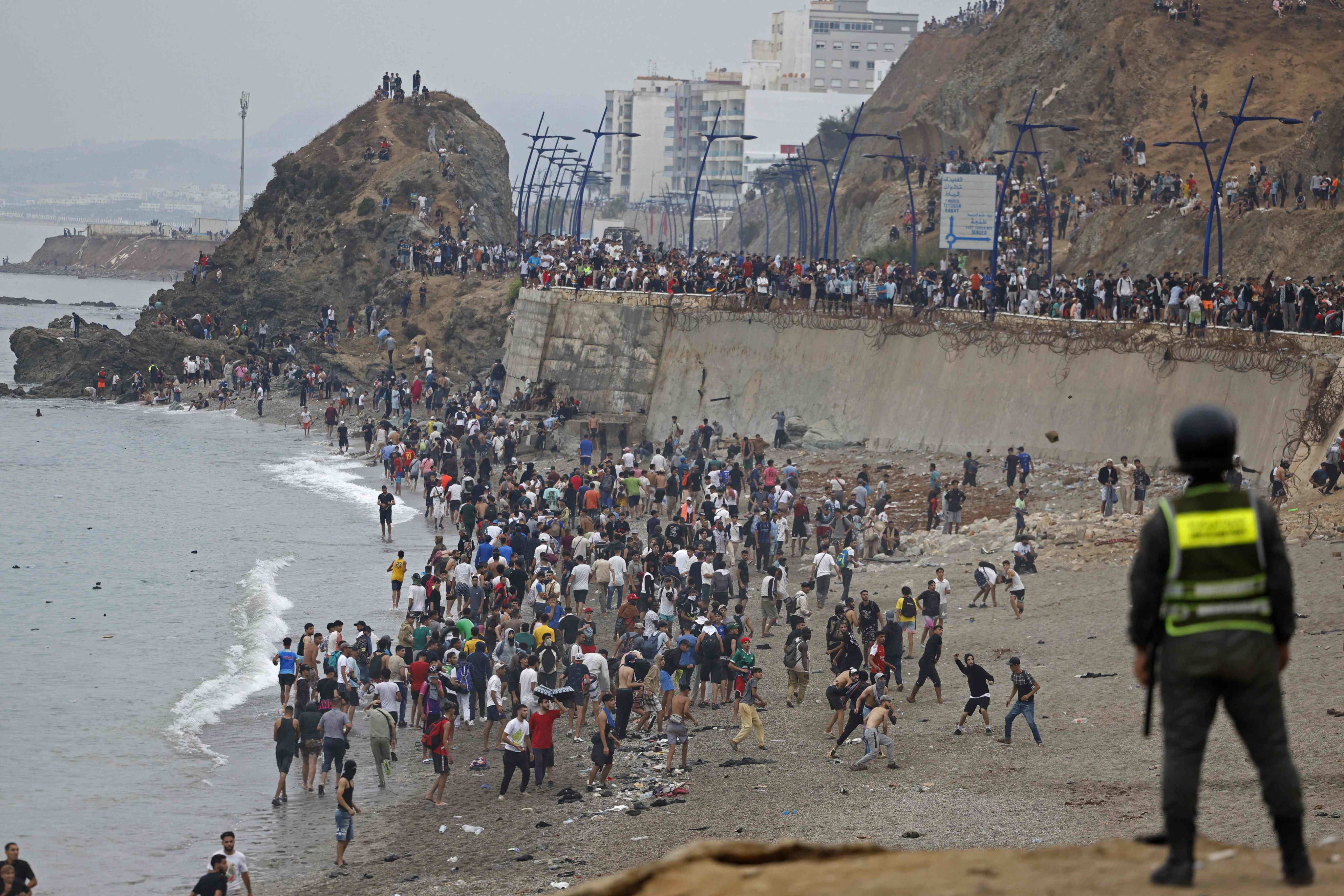 People gather along the fence at the site of clashes near Fnideq, on the Morocco-Spain border, on Friday. Photo: AFP