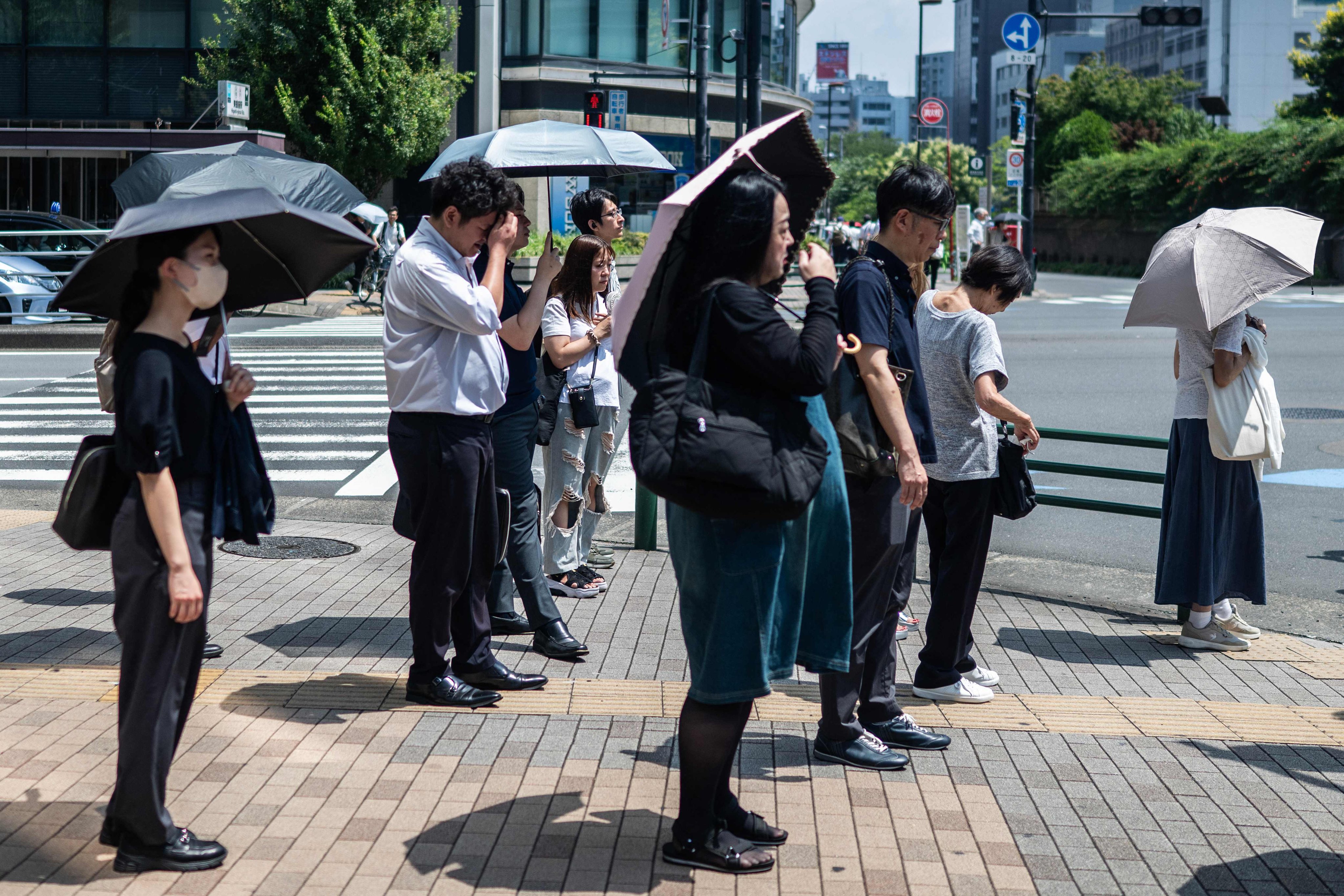 People carry umbrellas to shelter from the sun in Tokyo on July 23. Photo: AFP