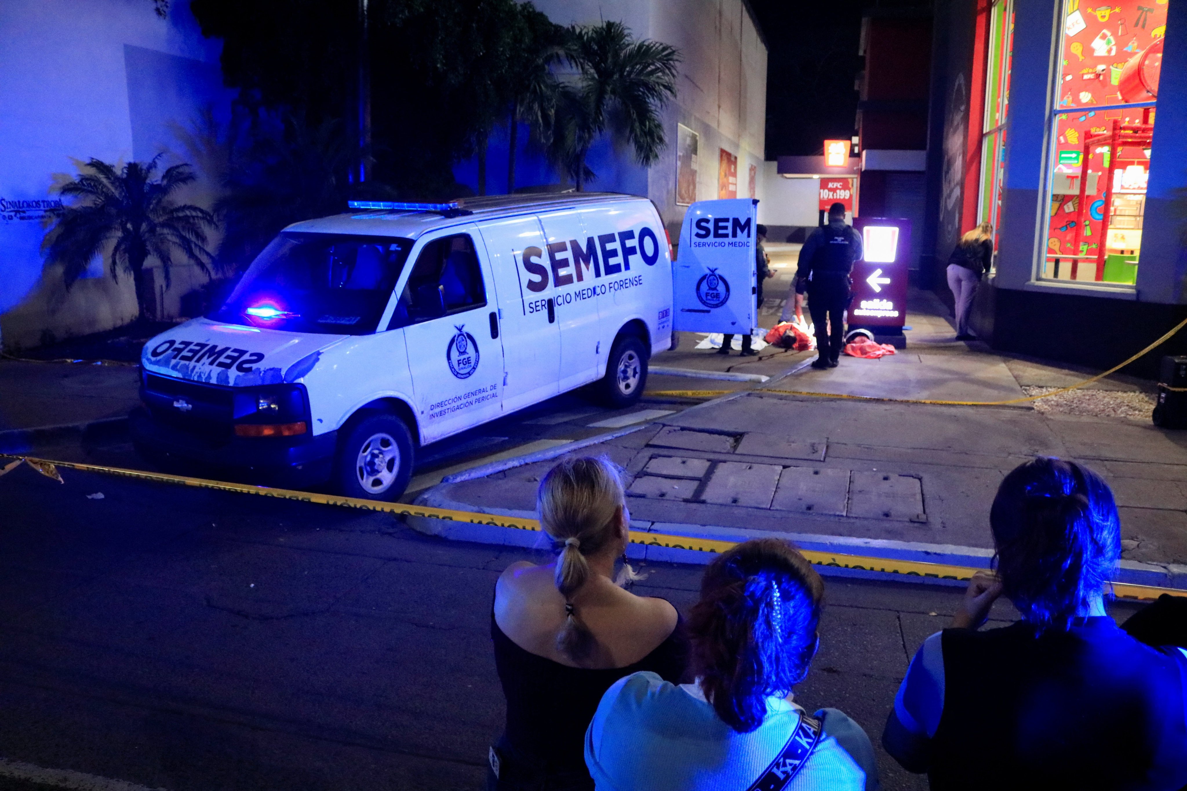 Onlookers stand behind a police cordon as forensic technicians and police officers work at the crime scene where Mexican social media influencer Cesar Gastelum was shot and killed while livestreaming outside a fast-food restaurant in Culiacan, Sinaloa state, Mexico on Tuesday. Photo: Reuters