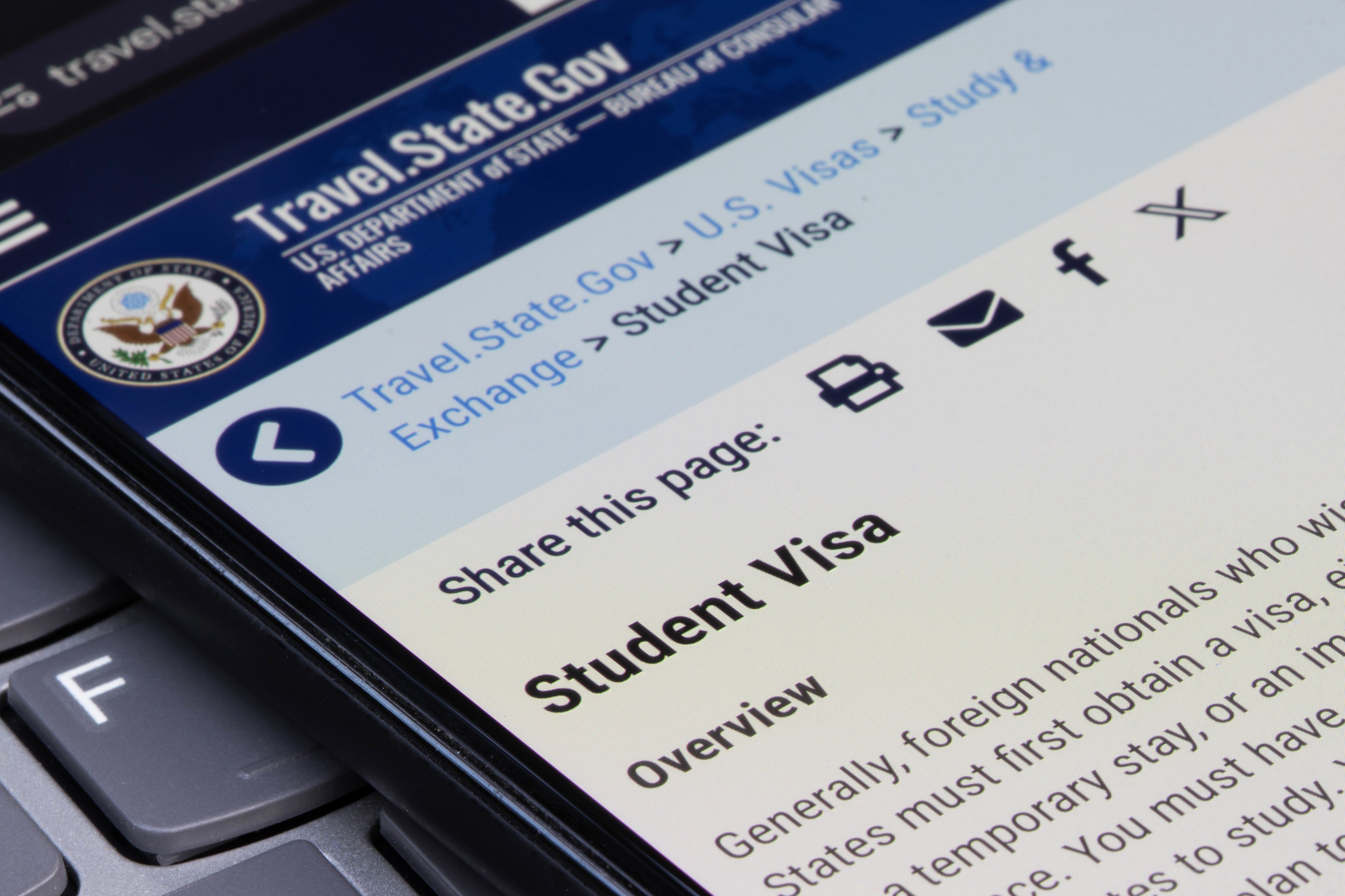 The US Department of State website’s student visa page on the screen of a smartphone. Photo: Shutterstock Images
