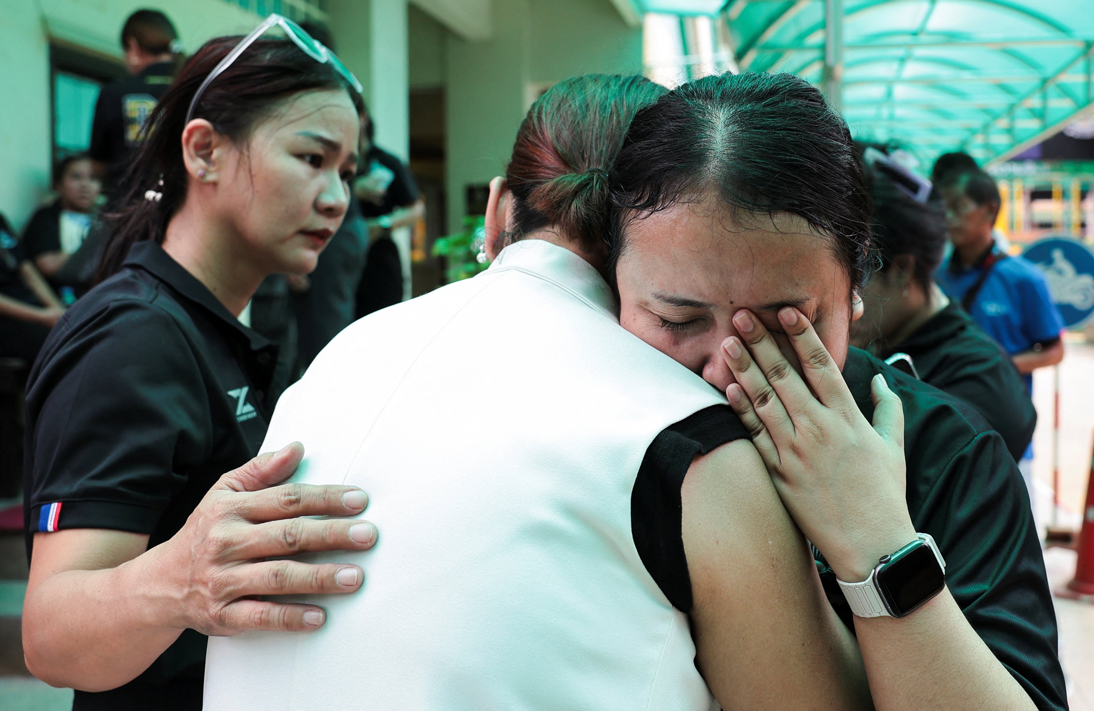 A teacher reacts while embracing a person at Debsirin Nonthaburi School in Thailand. Photo: Reuters