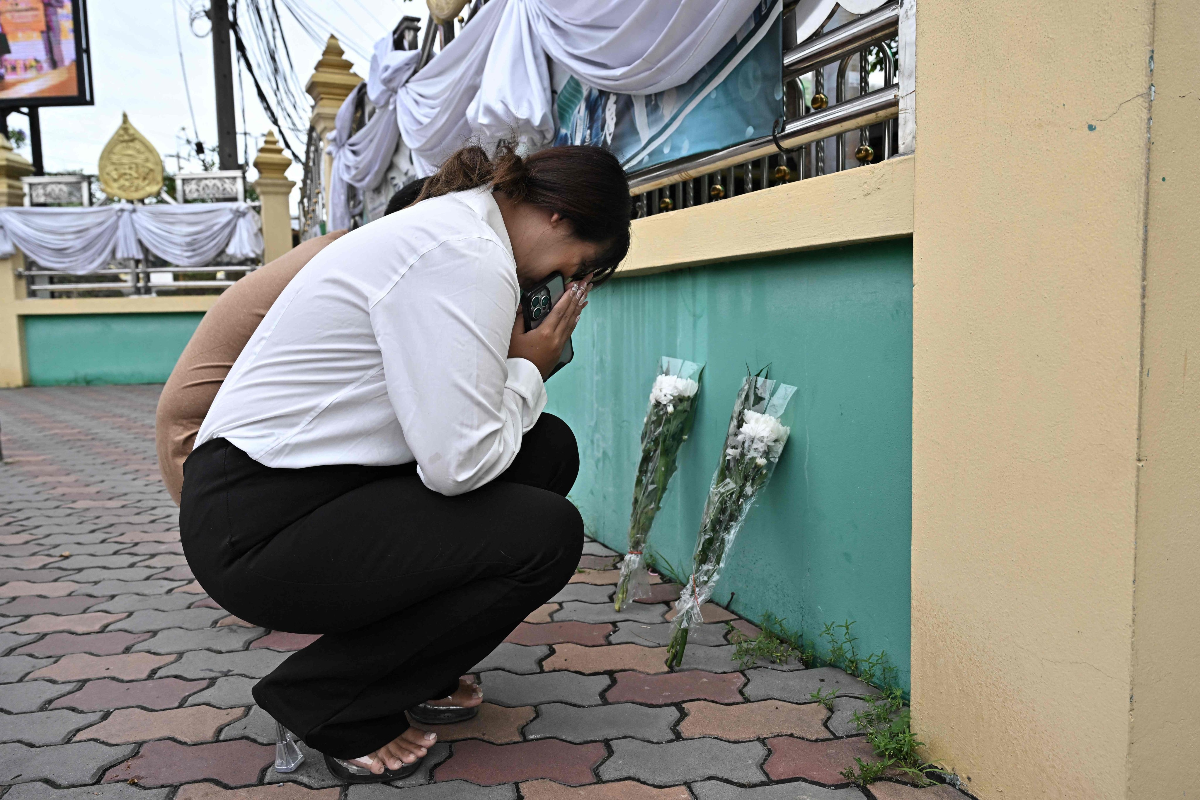 People leave flowers outside Debsirin Nonthaburi secondary school on Saturday, the day after a 14-year old pupil went on the rampage with a gun. Photo: AFP