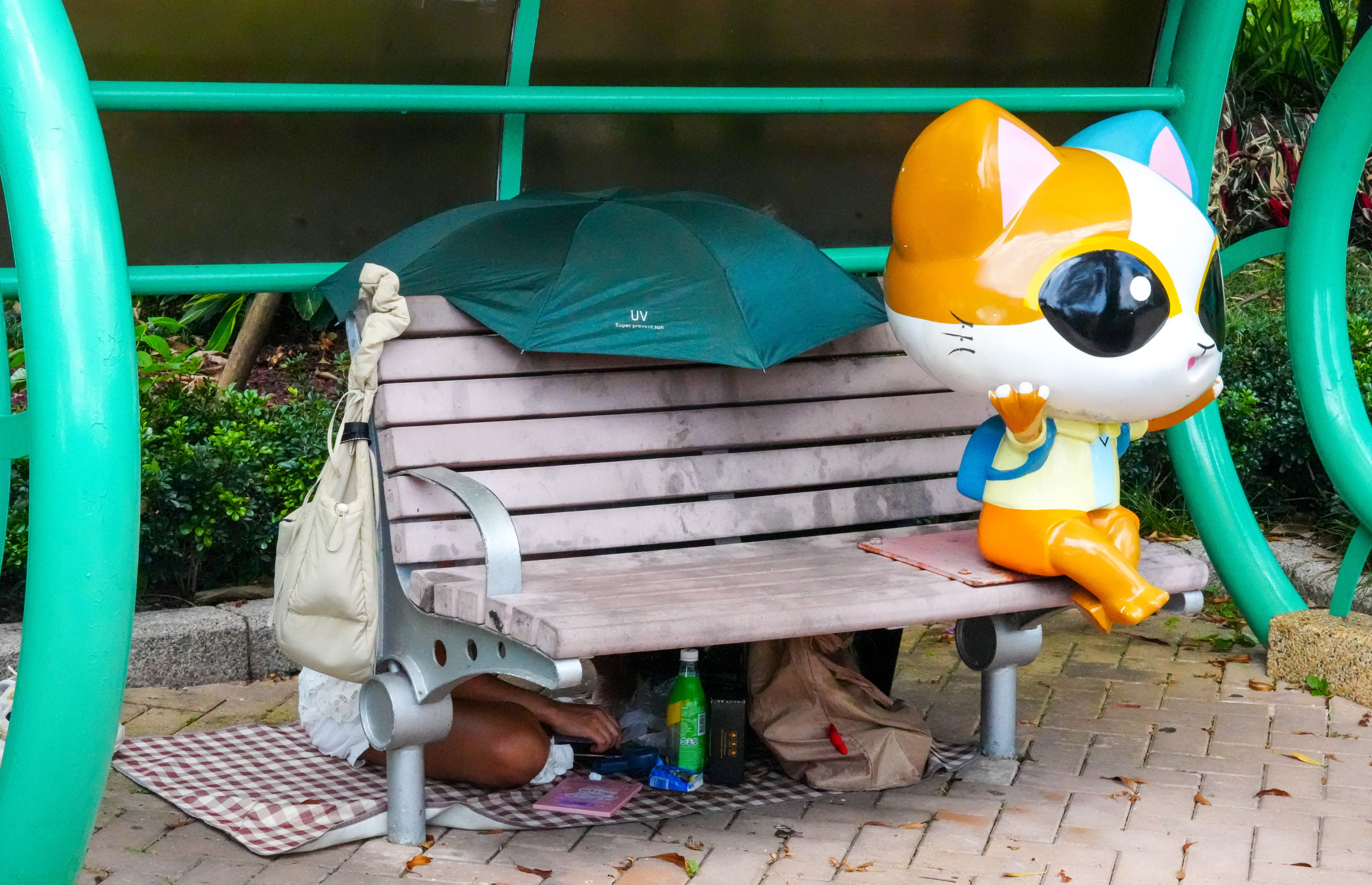 Domestic helpers take shelter from the intense heat behind a bench at Tsuen Wan Promenade. Photo: Dickson Lee