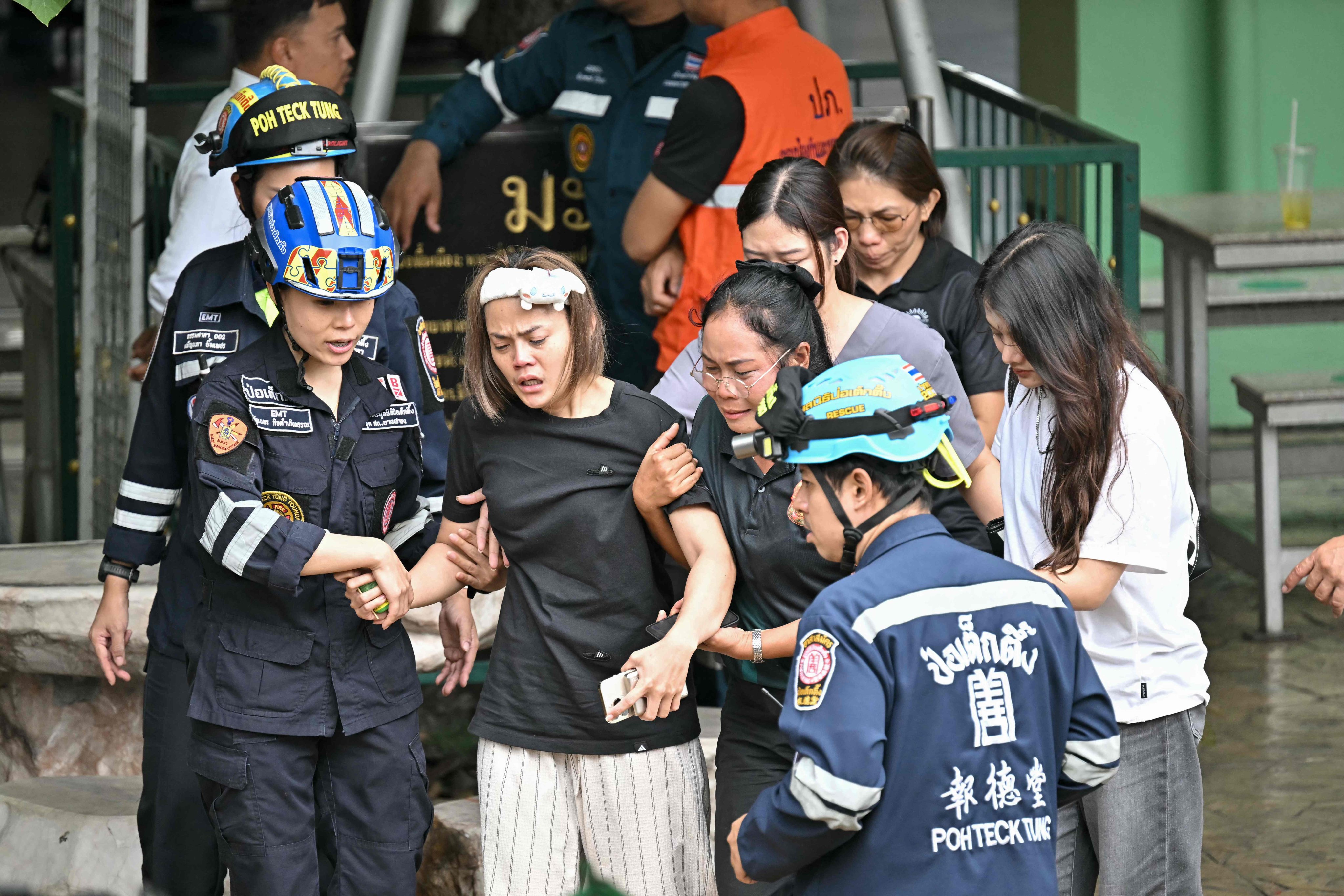 The wife (centre) of a Thai teacher who was killed in a school shooting is led to an ambulance in Nonthaburi province on Friday. Photo: AFP