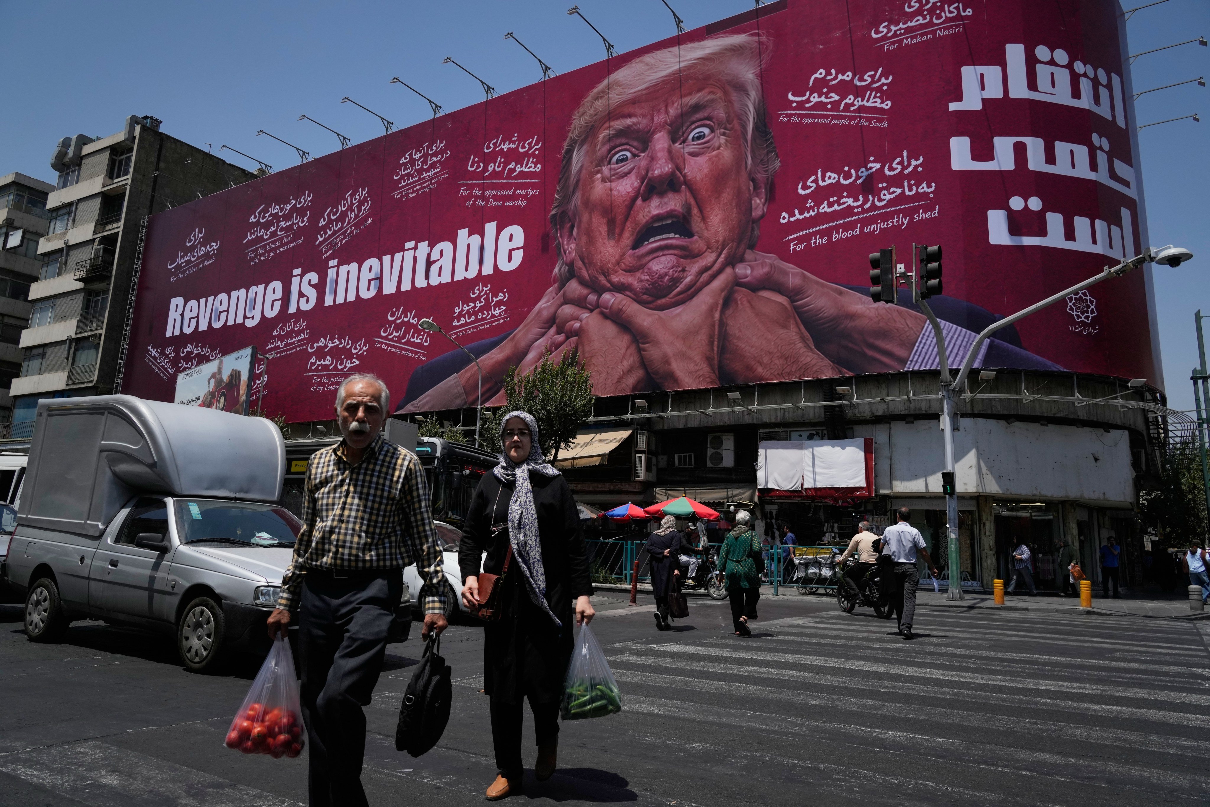 Pedestrians walk past a hoarding in Tehran in July depicting US President Donald Trump being grabbed by the neck alongside the message “Revenge is inevitable” in English and Farsi. Photo: AP