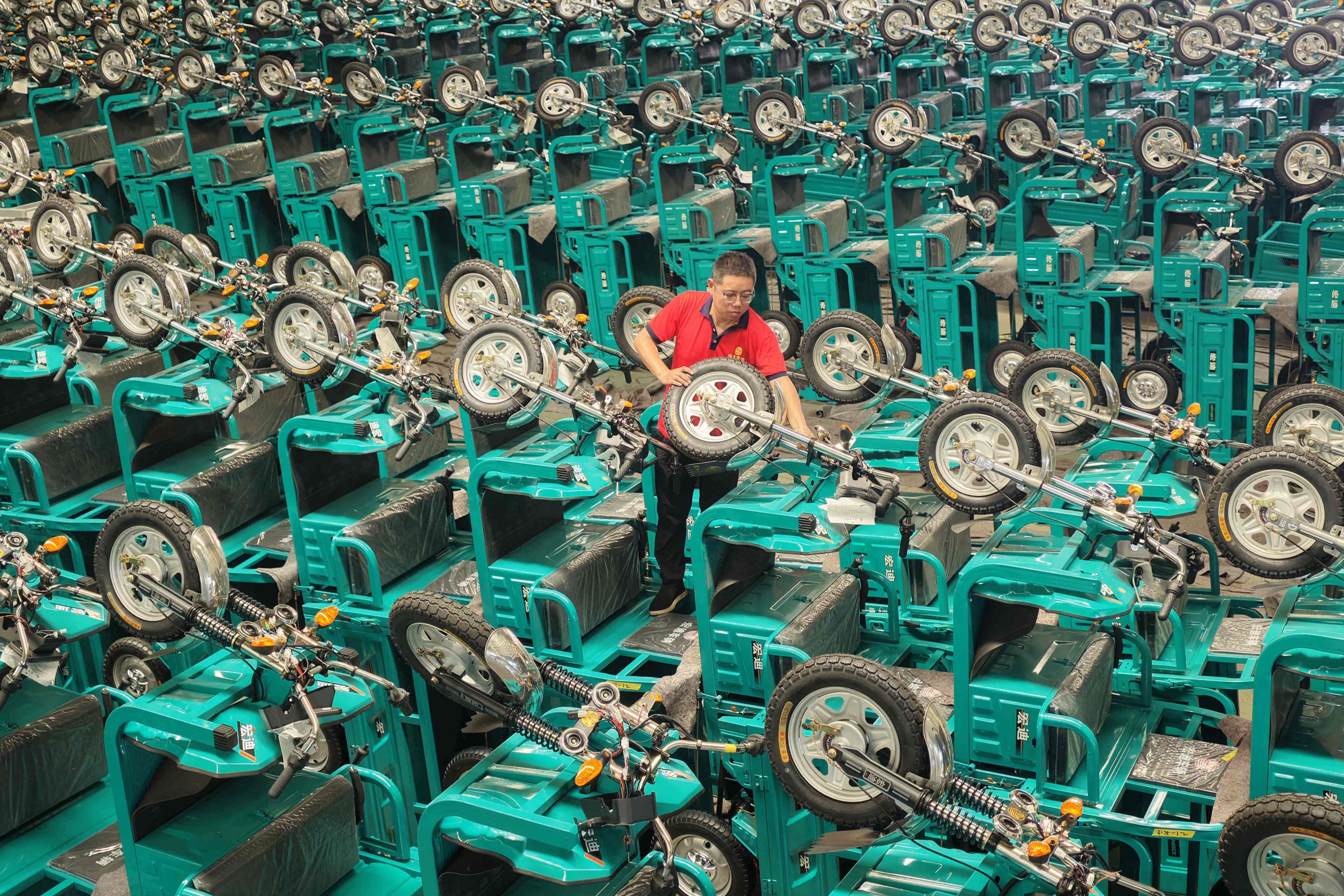 A staff member examines electric tricycles before shipment in China’s Shandong province on July 30, 2026. Photo: AFP