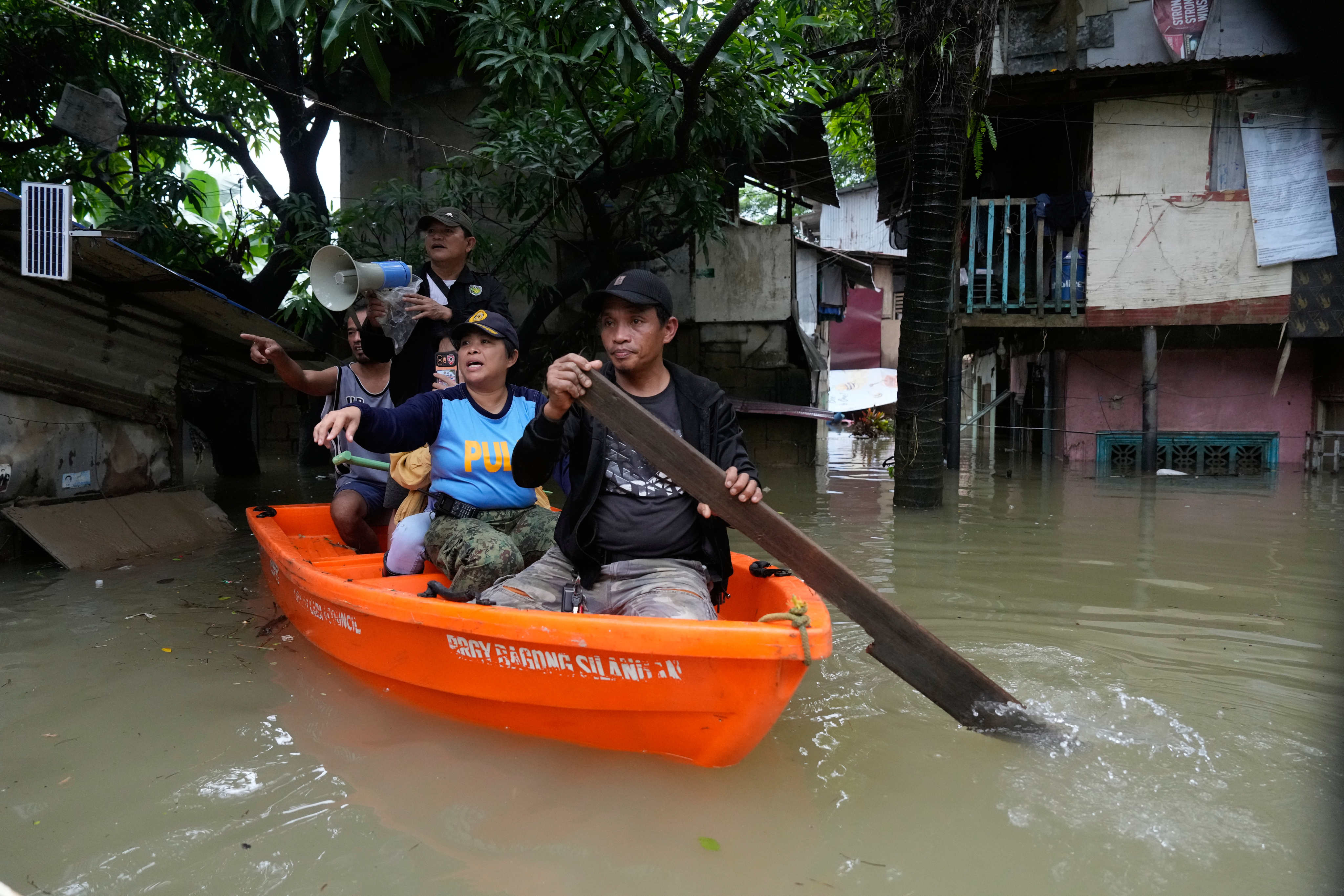 Police and officials remind residents to evacuate to higher ground as floodwaters inundate a village in Quezon City, Metro Manila, Philippines. Photo: AP