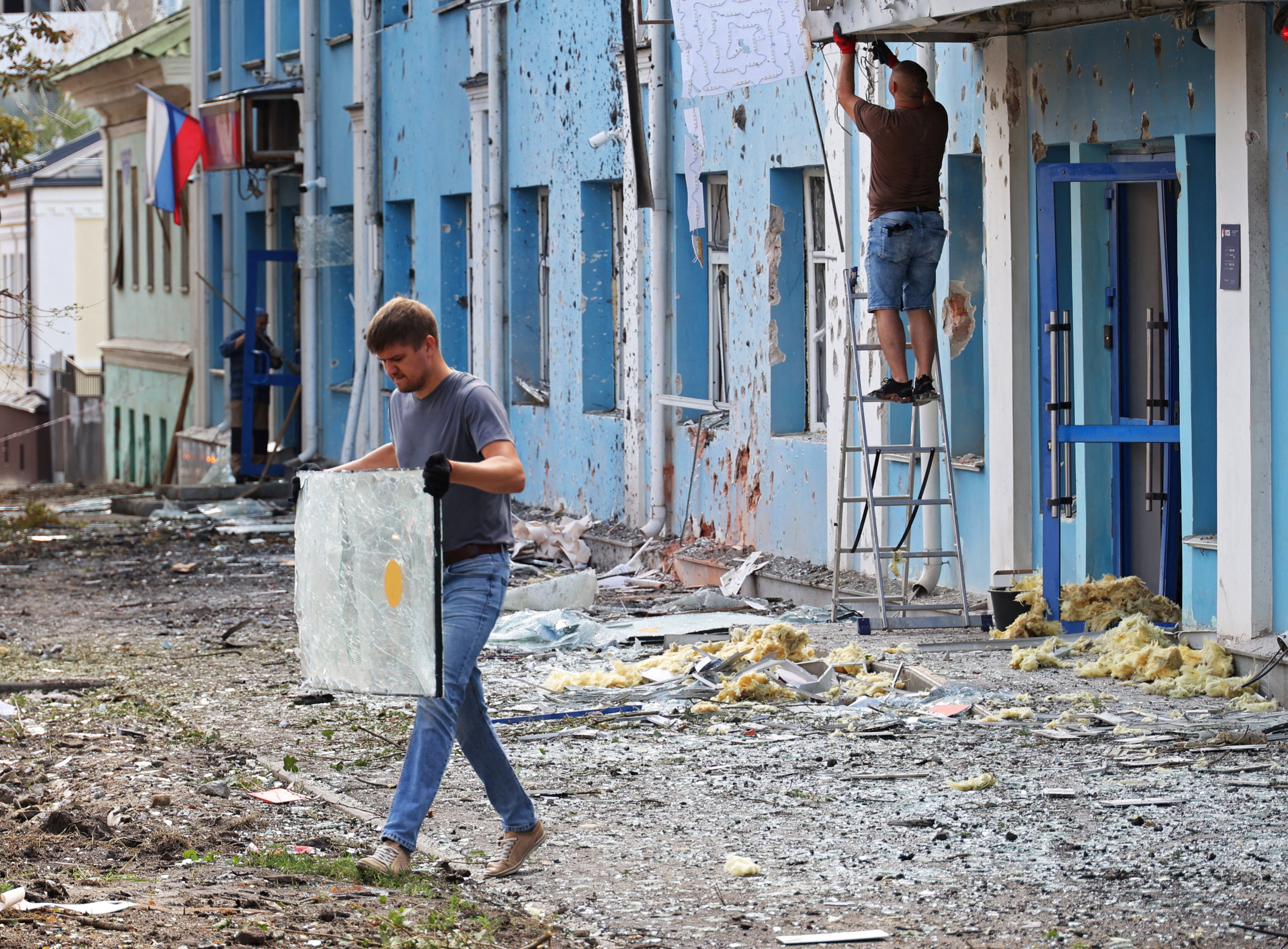 A man carries broken glass outside a bank building damaged during a Ukrainian overnight drone attack, according to local authorities, in Belgorod, Russia on Sunday. Photo: Reuters
