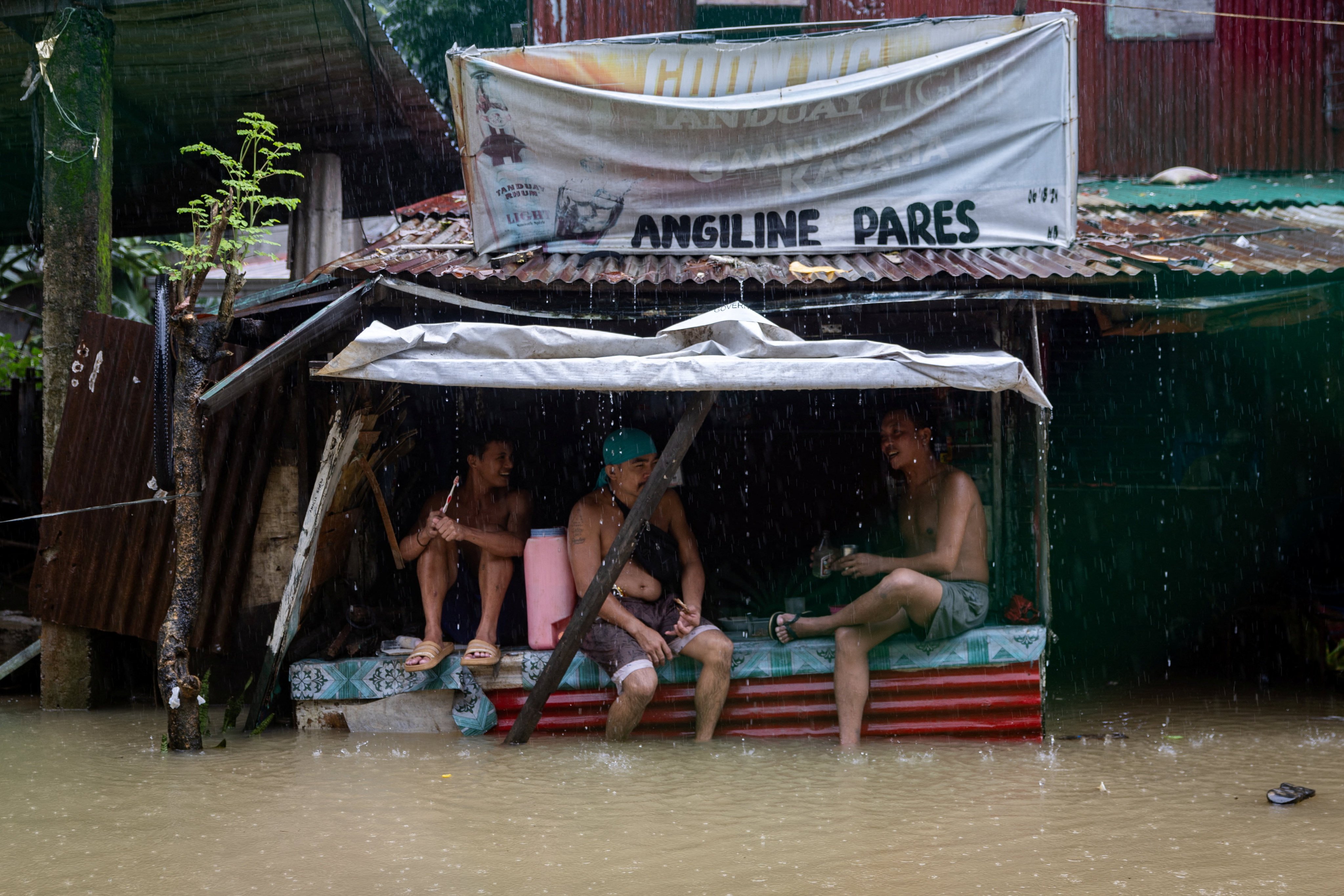Men drink and socialise at an inundated village, amid southwest monsoon rains in Bagong Silangan, Quezon City, Philippines. Photo: Reuters