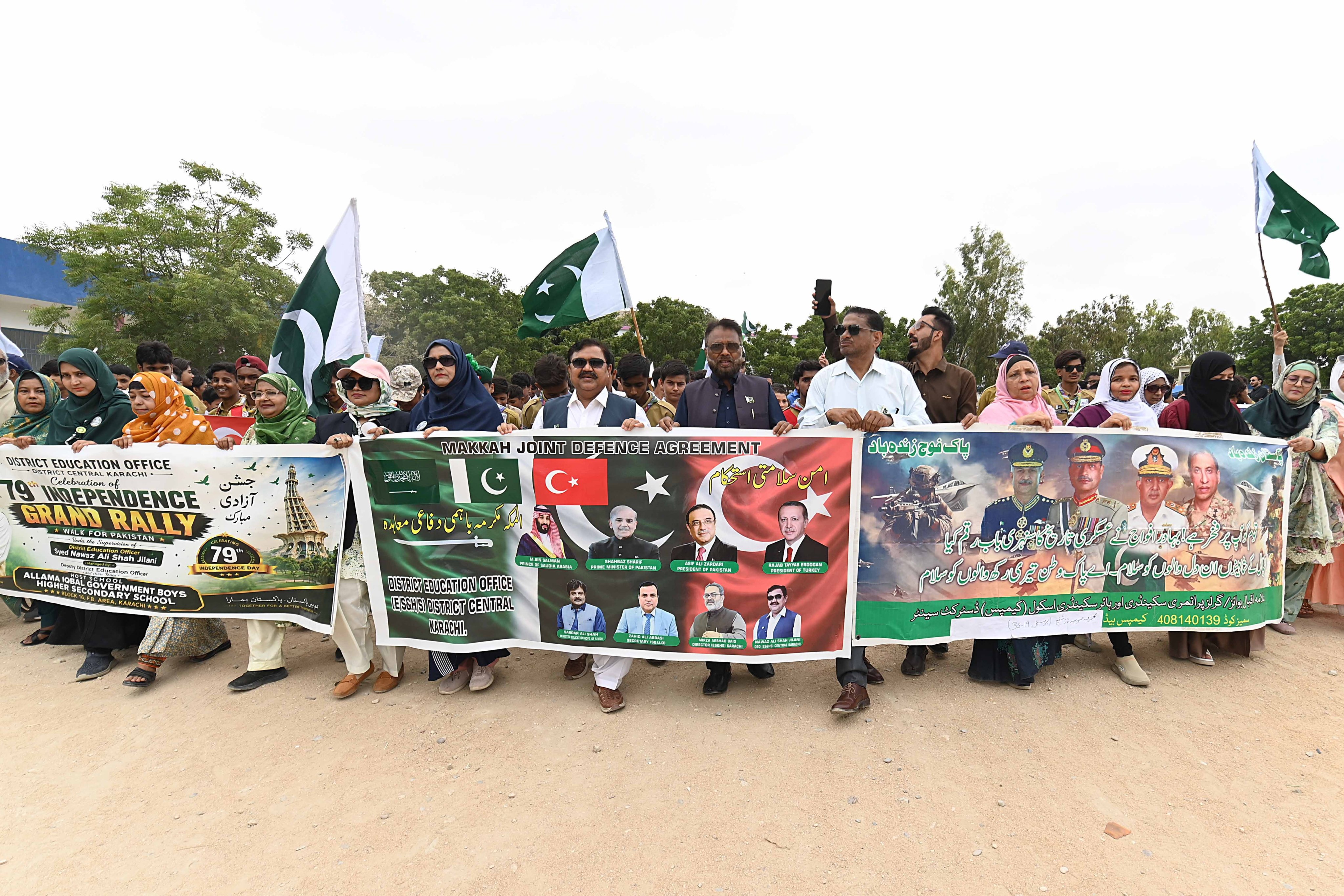 Pakistani people and students hold flags to celebrate the Pakistan-Saudi Arab-Turkish joint defence pact on Monday. Photo: EPA