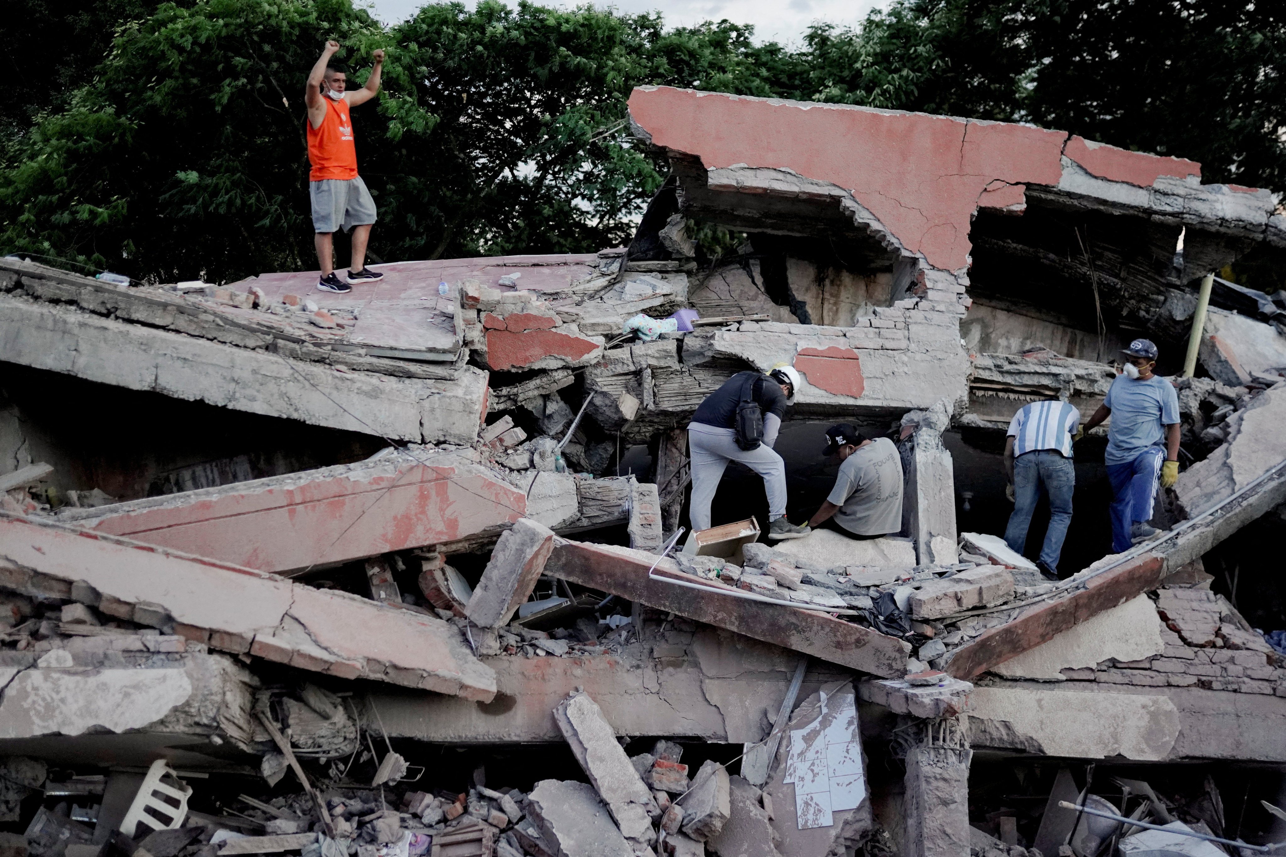 A rescue worker raises his fists to call for silence to locate victims under the rubble at the site of a collapsed building following an earthquake, in Cali, Colombia. Photo: Reuters
