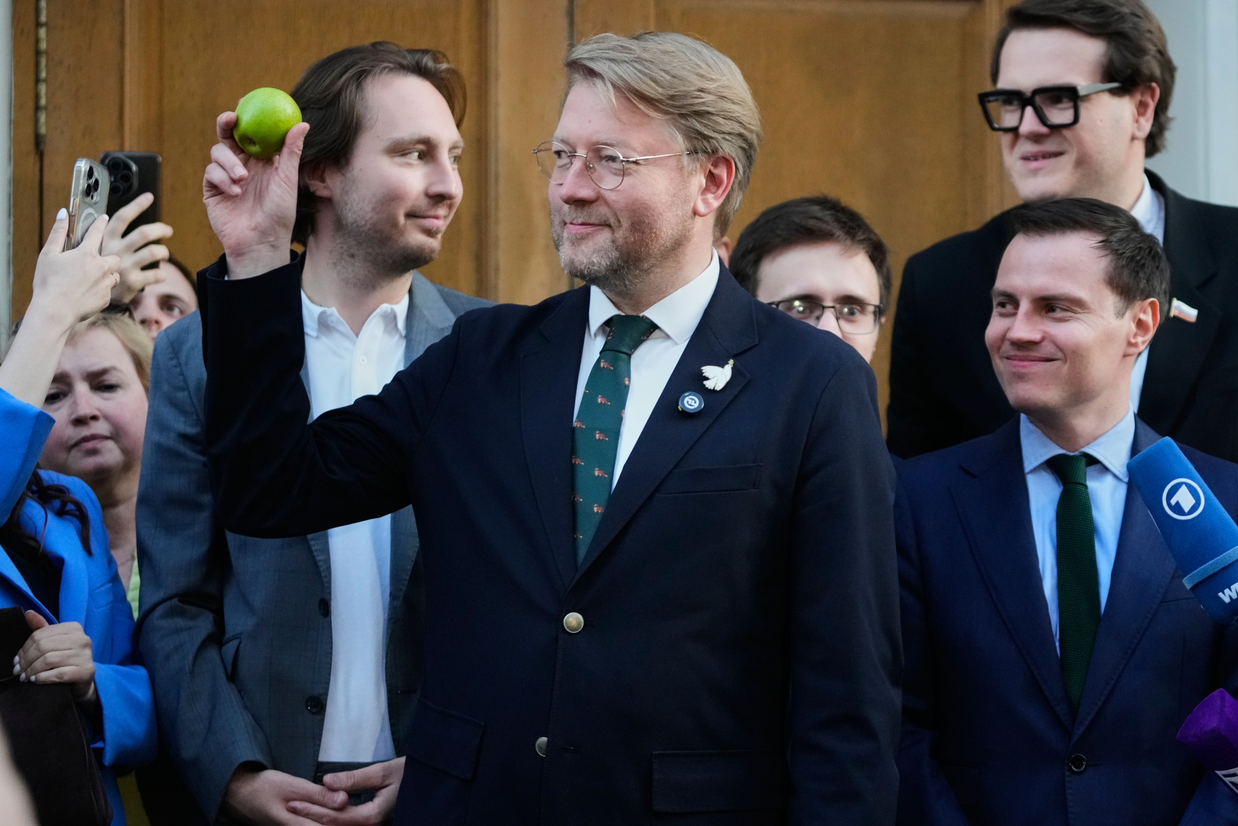 Yabloko party leader Nikolai Rybakov (centre) holds up an apple, the symbol of his party after a hearing on a lawsuit to bar the party from parliamentary elections, at the Supreme Court in Moscow, Russia on Monday. Photo: AP