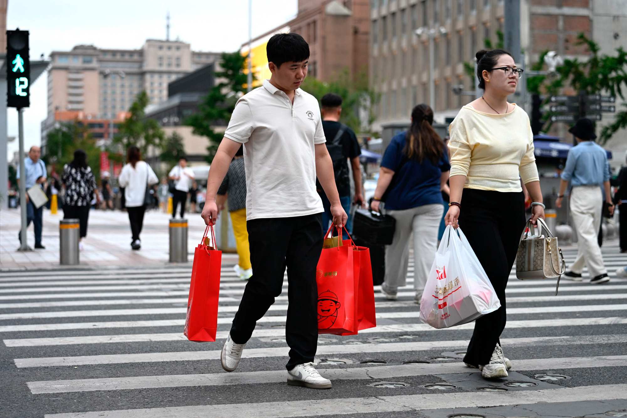 People carry shopping bags while crossing a street in Beijing on September 15. Photo: AFP People carry shopping bags while crossing a street in Beijing on September 15. Photo: AFP